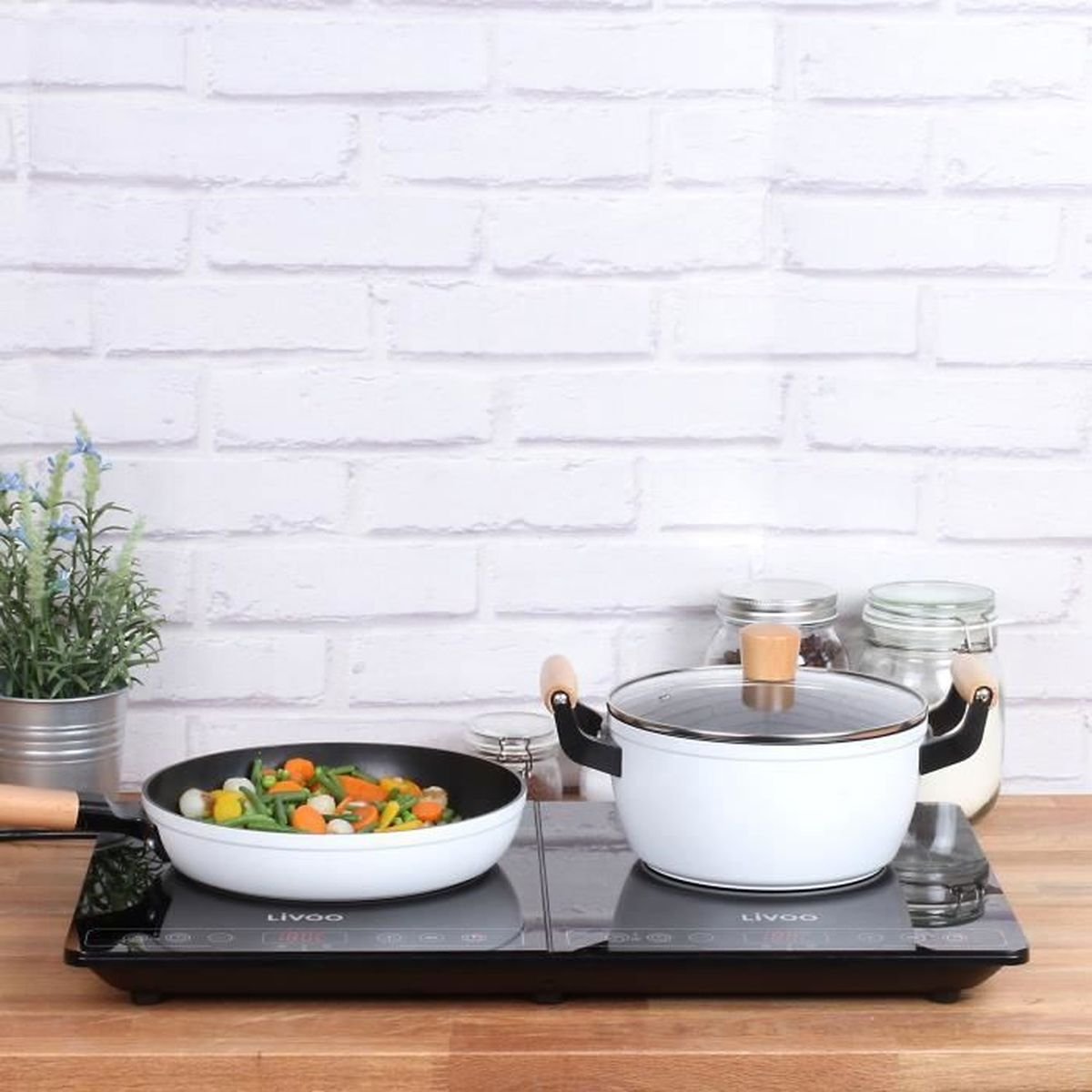 Biały garnek z warzywami na patelni. Powierzchnia do gotowania z białą ceglaną ścianą w tle.