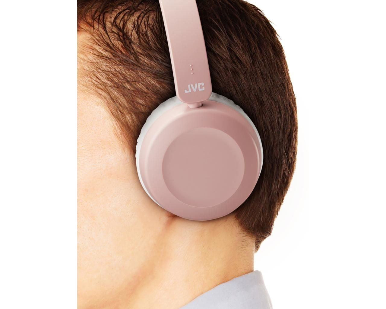 A person wearing pink JVC headphones. The headphones are around the ear and the person's brown hair is visible.