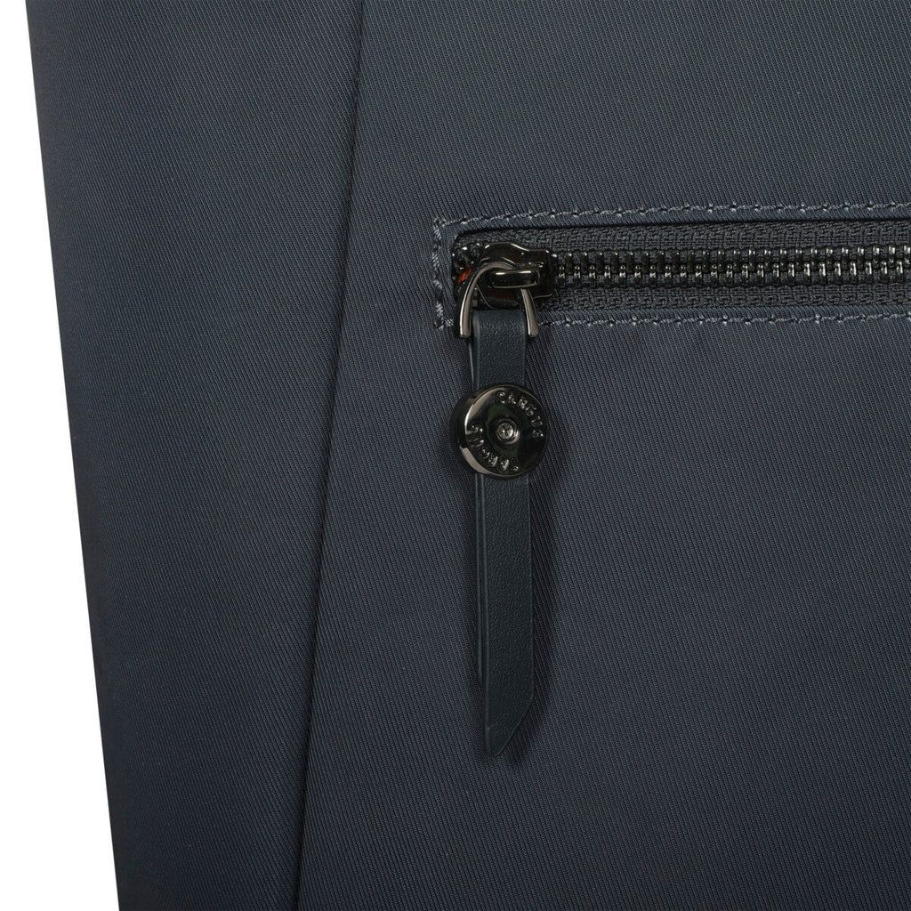 Nahaufnahme eines dunkelgrauen Stoffes mit Reißverschluss und Leder-Zuglasche. Der Reißverschluss ist metallisch und die Lasche hat einen Metallknopf.