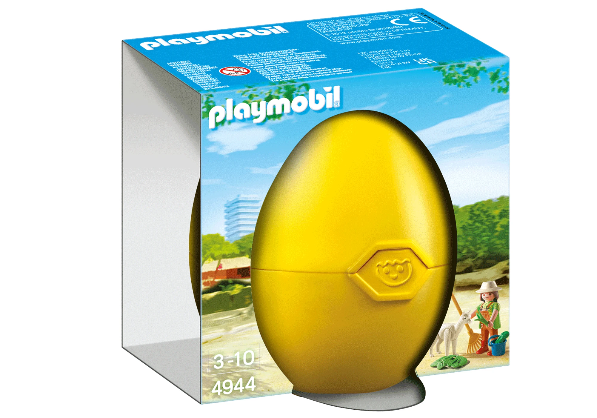 Playmobil Ei-Spielzeugbox. Ein gelber eiförmiger Behälter mit einer Kinderfigur, die eine Ziege putzt, auf einem Strandhintergrund.