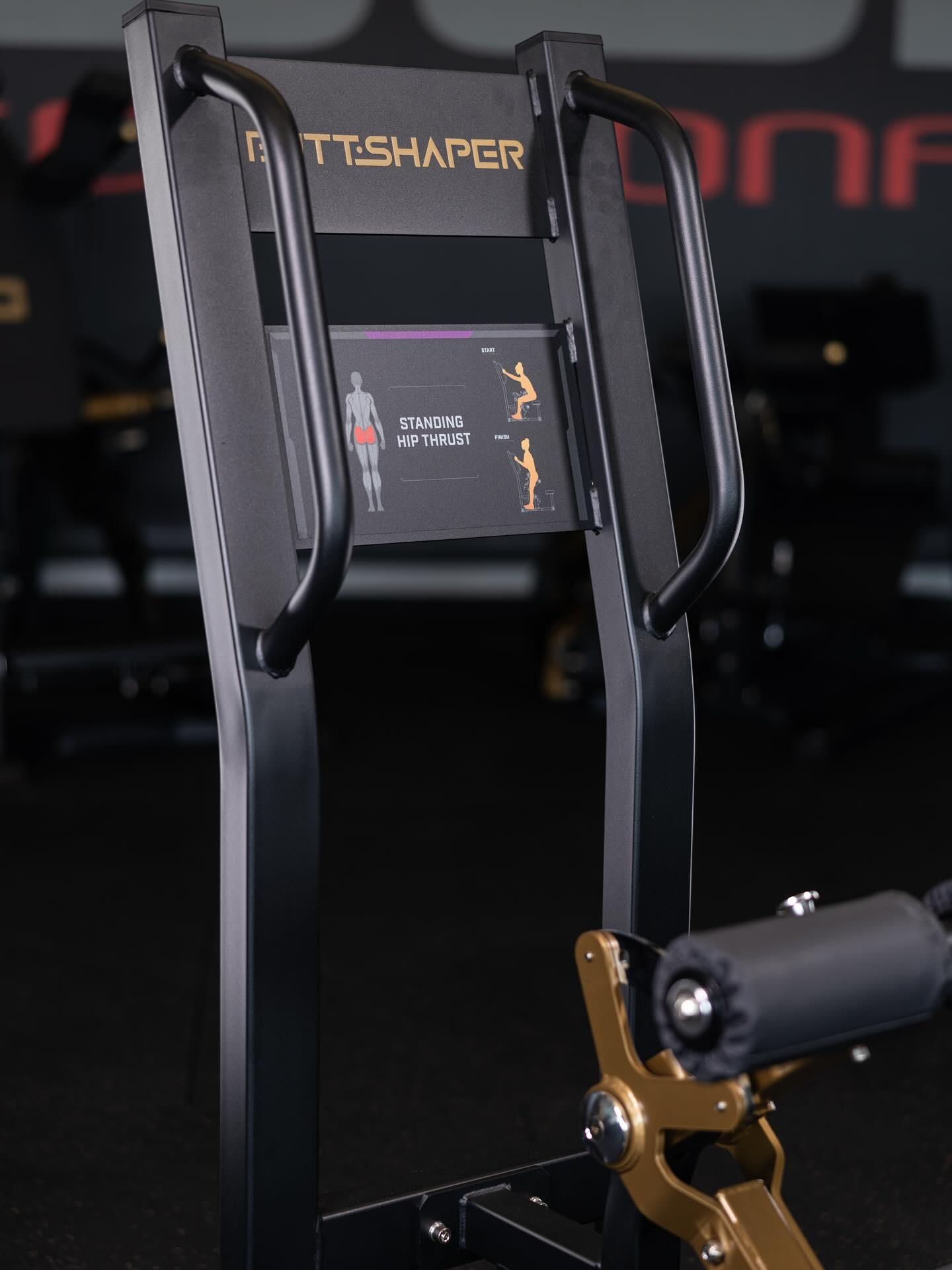 Zwarte en gouden Butt Shaper machine in een sportschool. Instructies voor heupduwen zichtbaar.