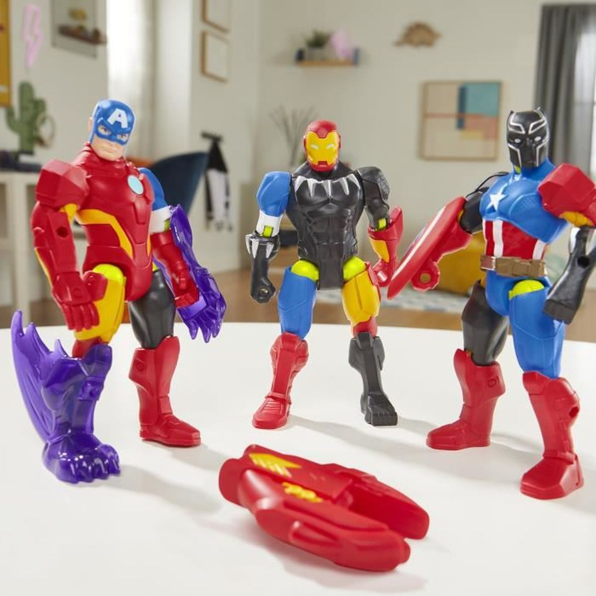 Drei Superhelden-Actionfiguren: Captain America, Iron Man und Black Panther. Eine rote Waffe liegt davor auf einem weißen Tisch.