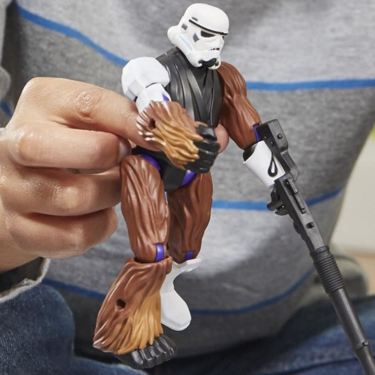 Una figura de acción híbrida de Star Wars está sujeta. Es una cabeza de Stormtrooper, cuerpo de piel marrón y un arma negra. Lo sostiene una persona.