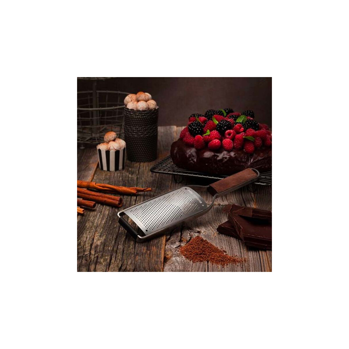 Eine Reibe, Kuchen mit Beeren, Schokolade, Zimt und Cupcakes auf einem Holztisch. Die Szene ist gut beleuchtet und einladend.
