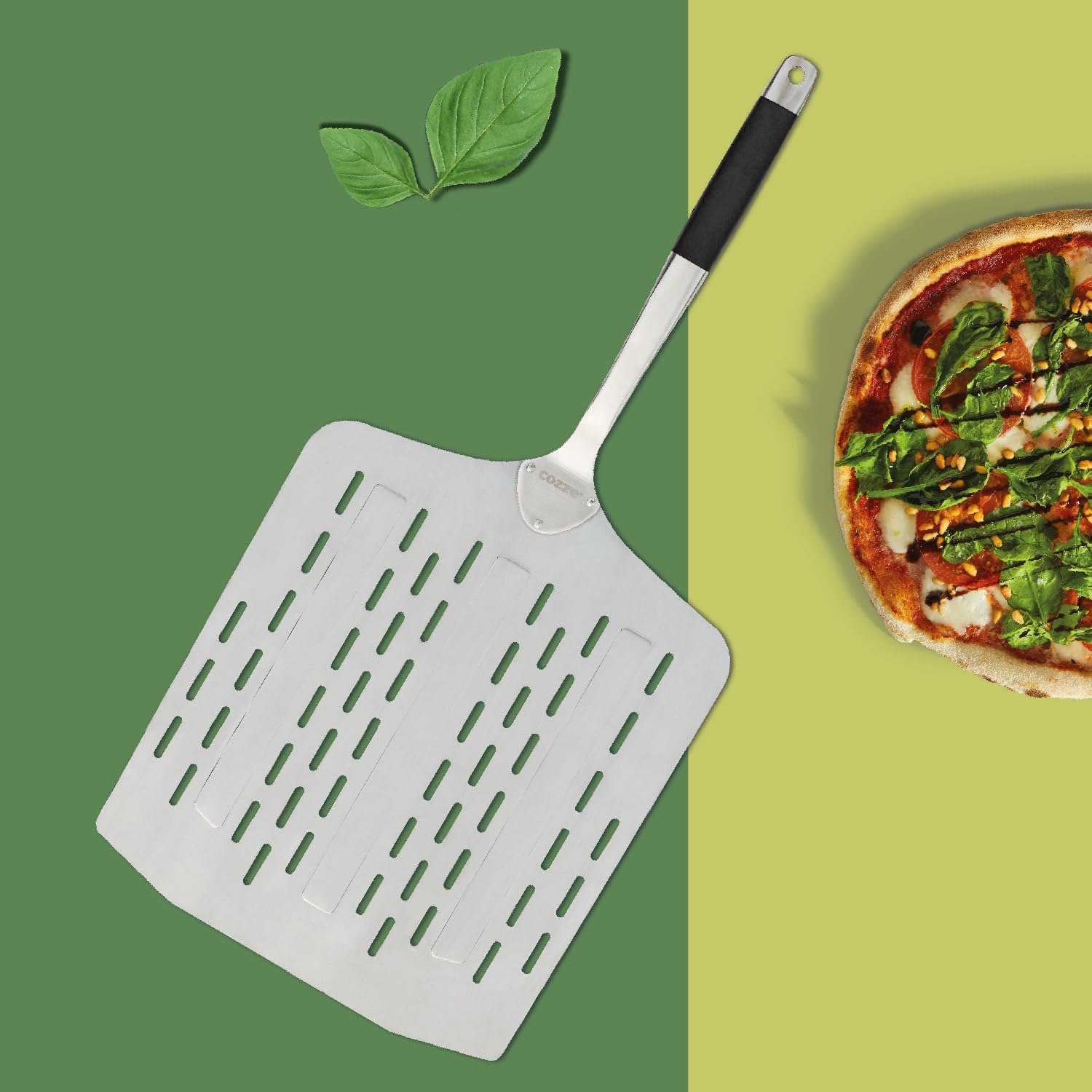 Eine Pizzaschaufel neben einer Pizza. Die Pizza hat Basilikum, Käse und Pinienkerne. Grüne und gelbe Hintergründe.