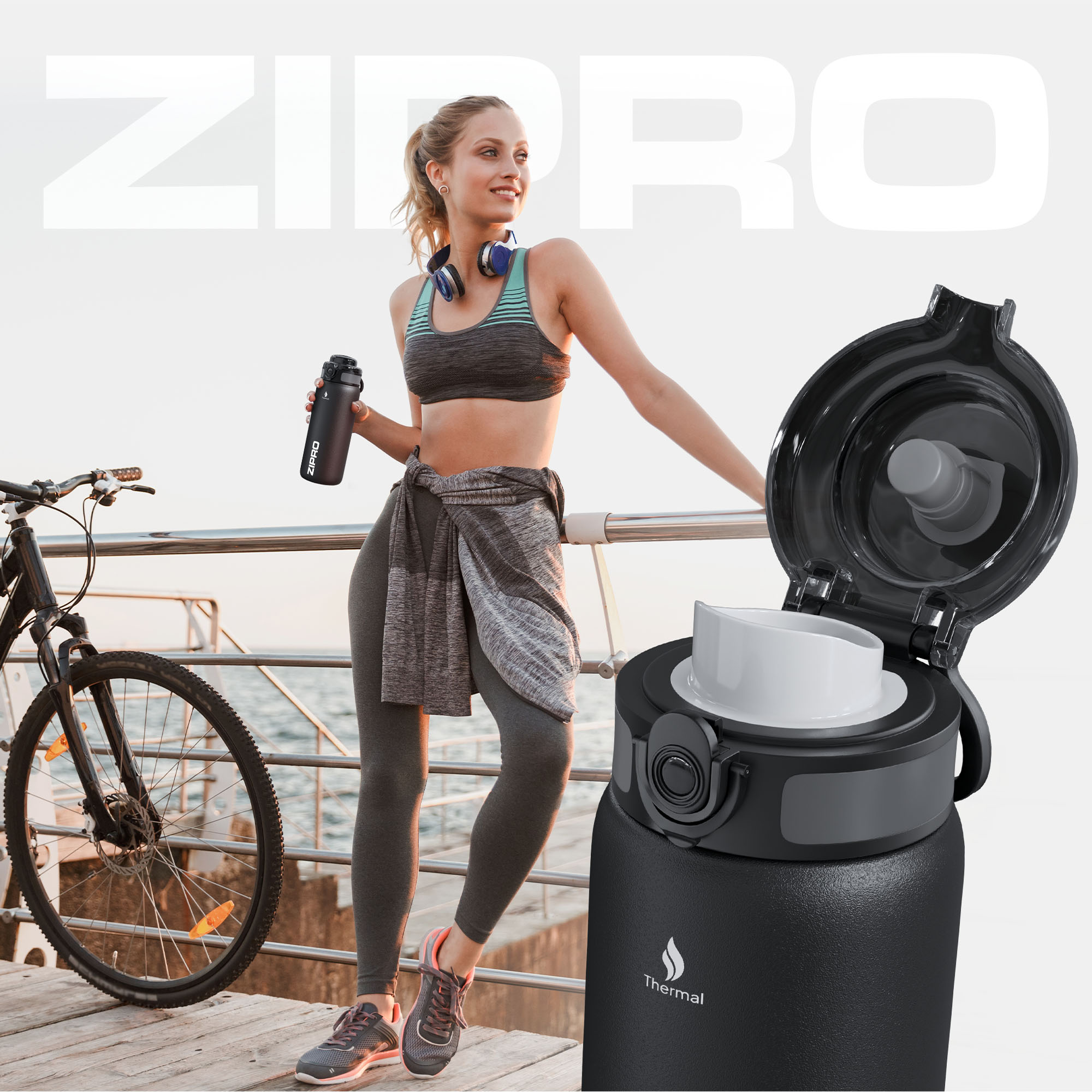 Frau mit Kopfhörern und einer Wasserflasche steht neben einem Fahrrad. Die Flasche ist schwarz mit offenem Deckel. Meer im Hintergrund.