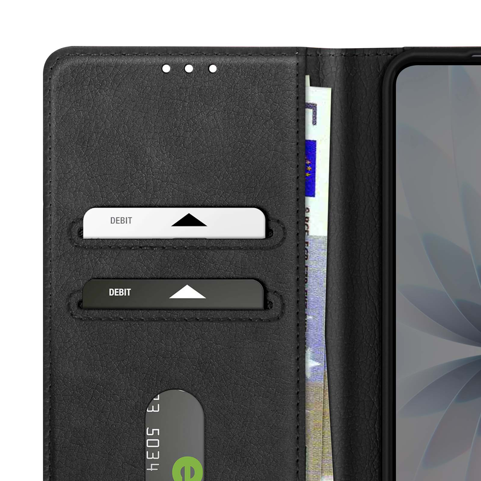 Portafoglio nero con due fessure per carte di debito, una banconota in euro e un telefono. Le carte sono bianche con DEBITO.