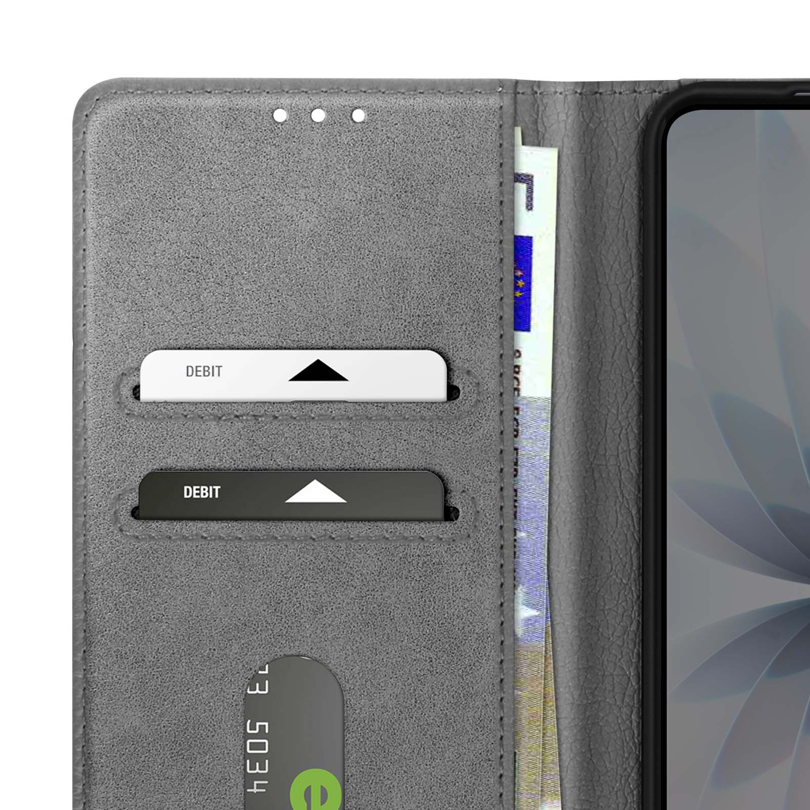 Portafoglio grigio con carte di debito e denaro visibili. Un telefono a destra. Il portafoglio è aperto.