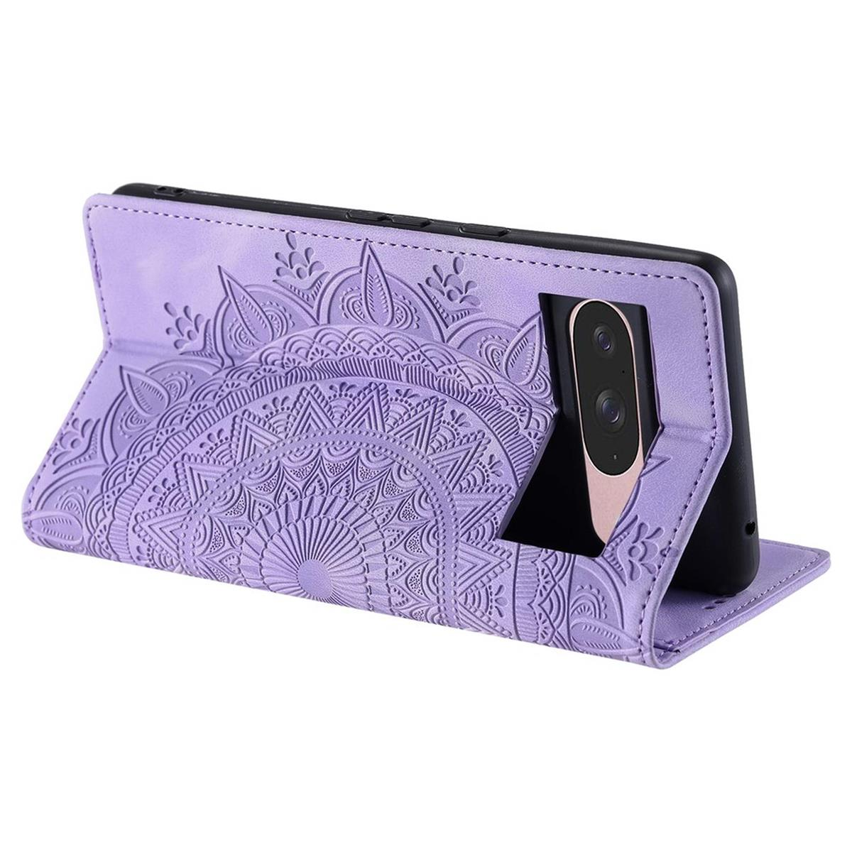 Eine lila Handyhülle mit Mandala-Design ist geöffnet und hält ein schwarzes Handy. Die Hülle liegt auf einer weißen Oberfläche.