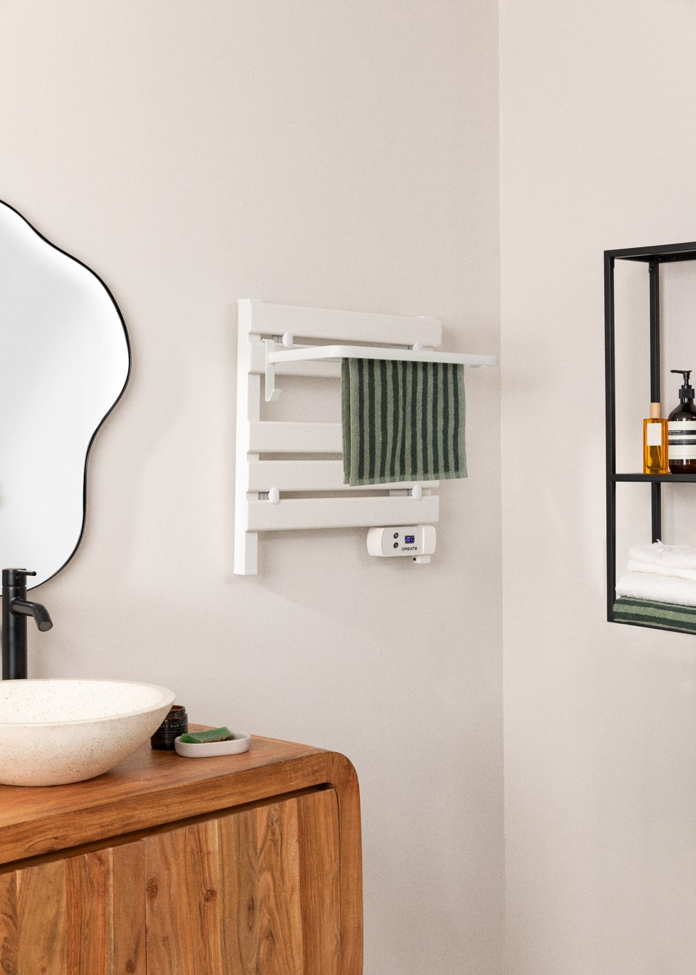 Escena de baño con un toallero blanco que sostiene una toalla a rayas verdes. Un espejo y un lavabo están en primer plano.