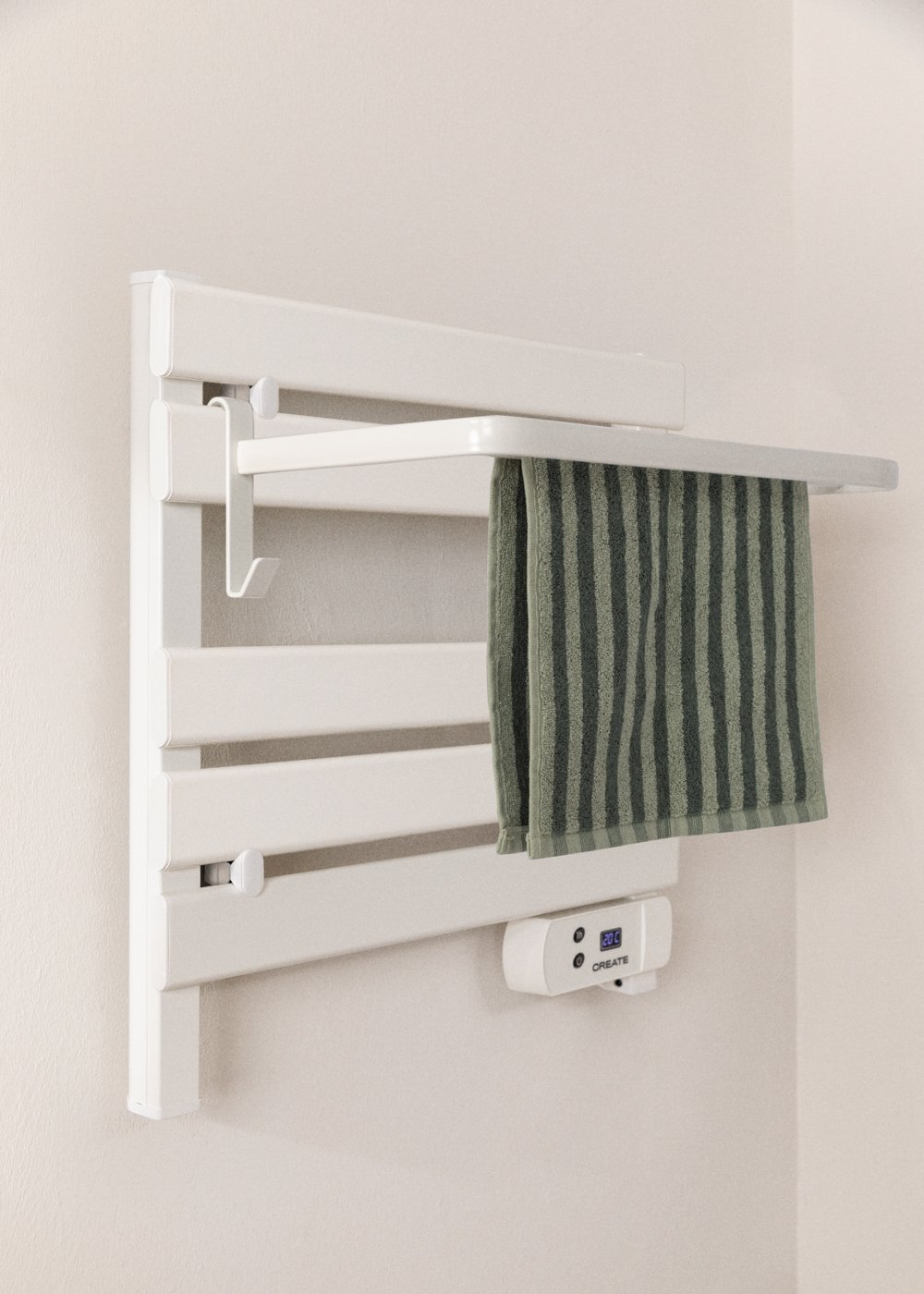 Toallero con calefacción blanco con toalla a rayas verdes. La pantalla digital muestra 20 grados. Montado en una pared beige.
