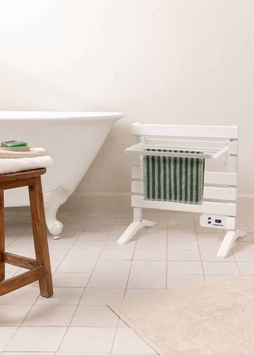 Escena de baño con toallero blanco, toalla a rayas verdes, taburete de madera y bañera blanca.