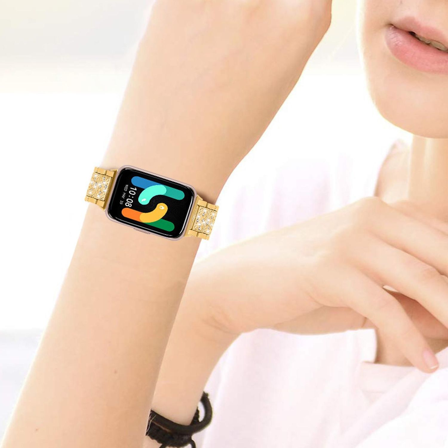 Das Handgelenk einer Frau mit einer goldenen Uhr. Die Uhr hat einen schwarzen Bildschirm, der die Zeit anzeigt. Das Armband ist goldfarben mit Edelsteinakzenten.