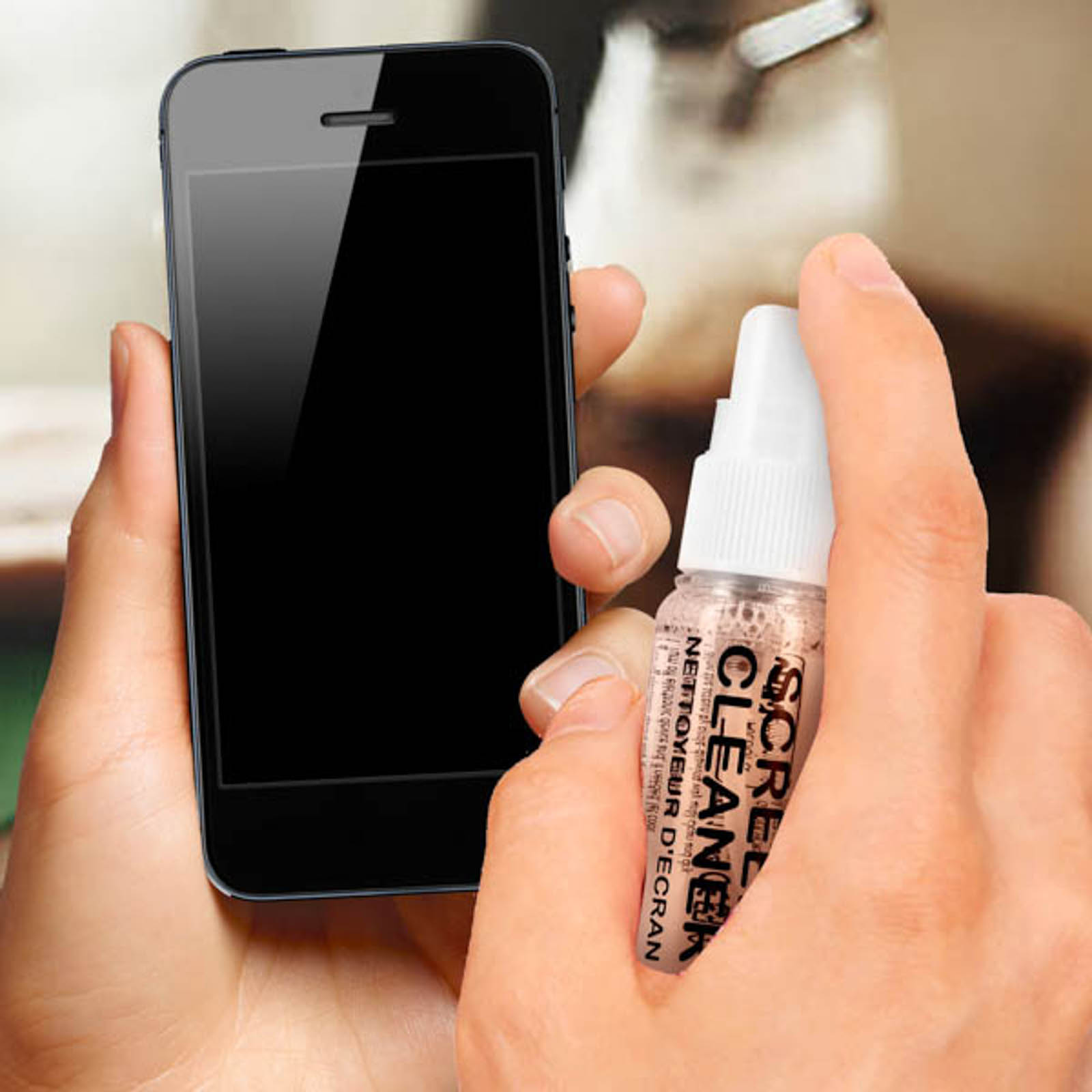 Una mano tiene uno smartphone nero, mentre l'altra spruzza detergente per schermo sul telefono.