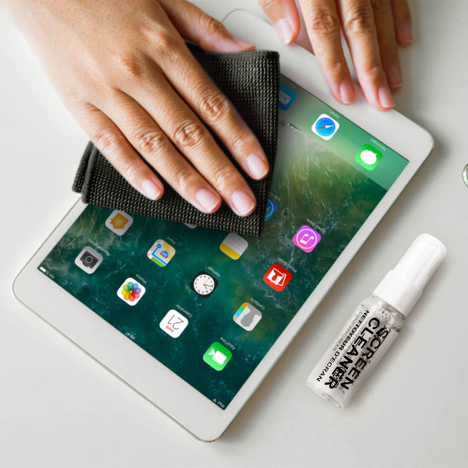 Una persona pulisce lo schermo bianco di un iPad con un panno nero. Accanto c'è uno spray per la pulizia dello schermo.