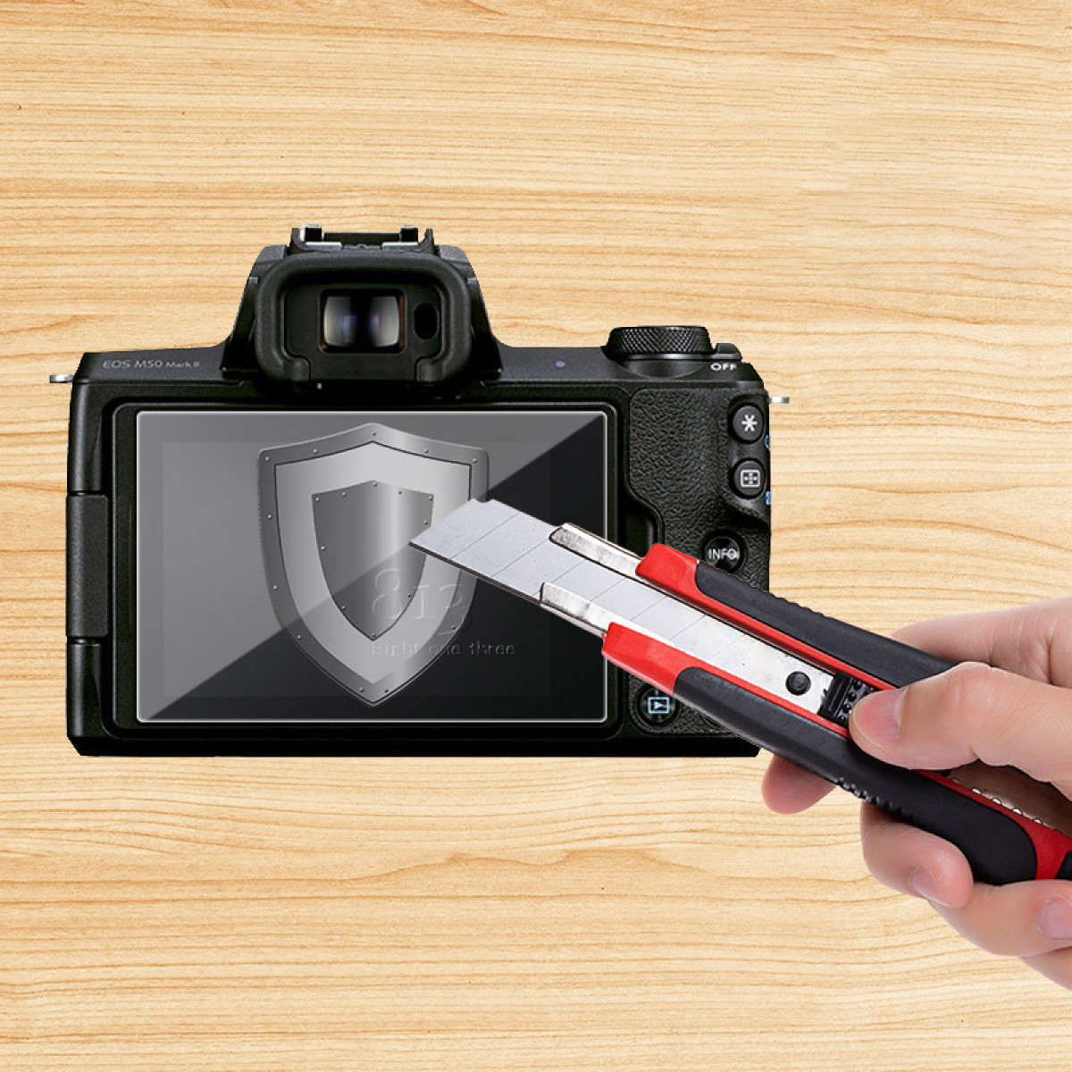 Ręka trzyma nóż do nakładania folii ochronnej na ekran aparatu na drewnianej powierzchni.