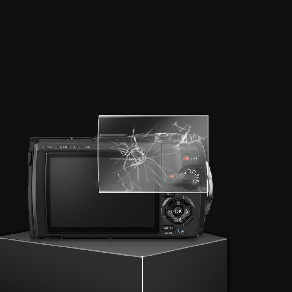 Czarny aparat Olympus Tough TG-3 stoi na czarnej platformie. Przezroczysta nakładka z efektem pękniętego szkła z przodu.