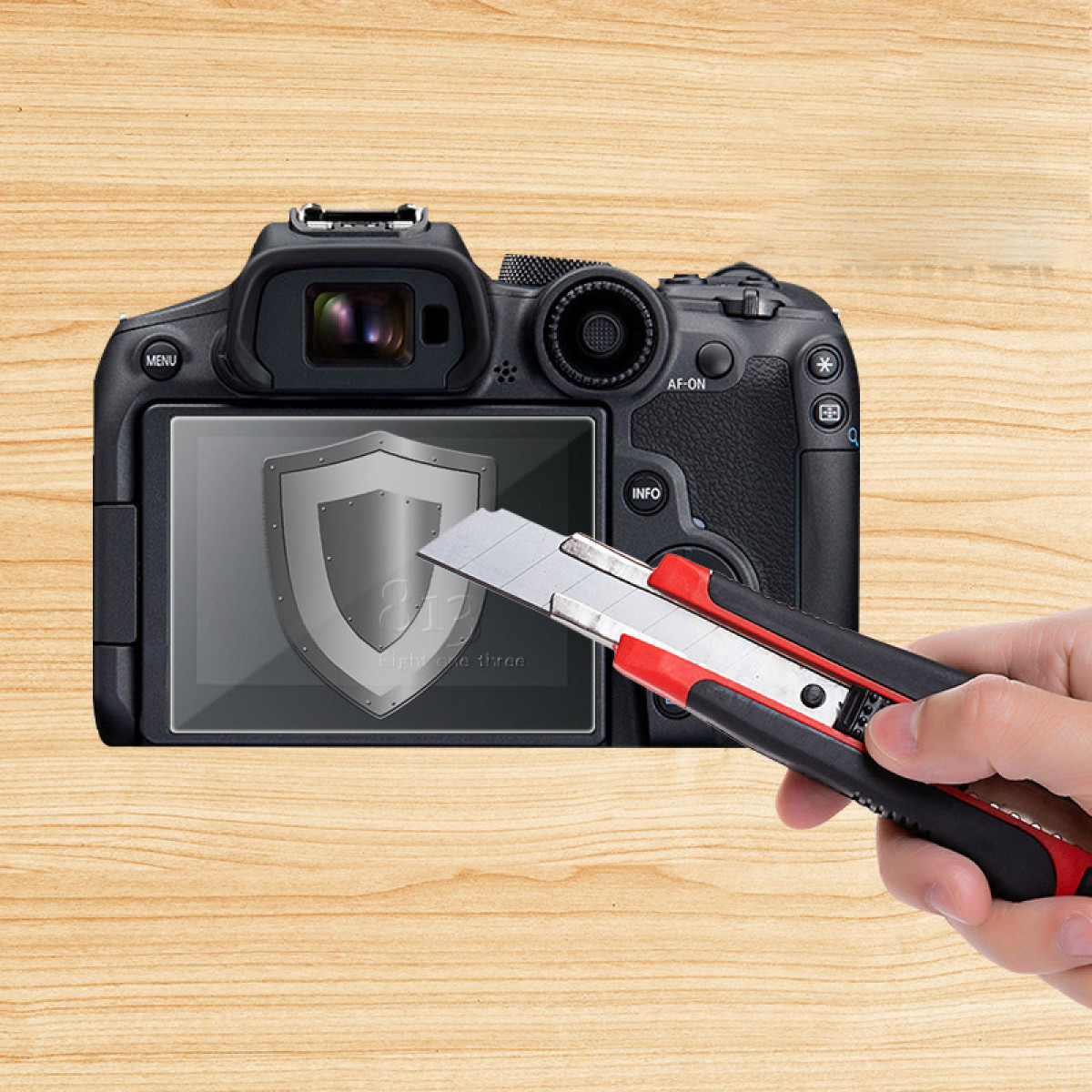 Aparat fotograficzny z ochraniaczem ekranu ciętym nożem. Tło to drewniana powierzchnia.