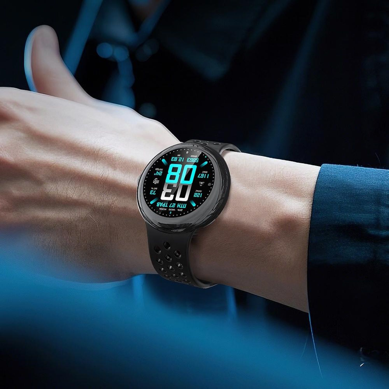 Polso di una persona con uno smartwatch nero che mostra dati. L'orologio ha un cinturino nero con fori. Lo sfondo è sfocato.