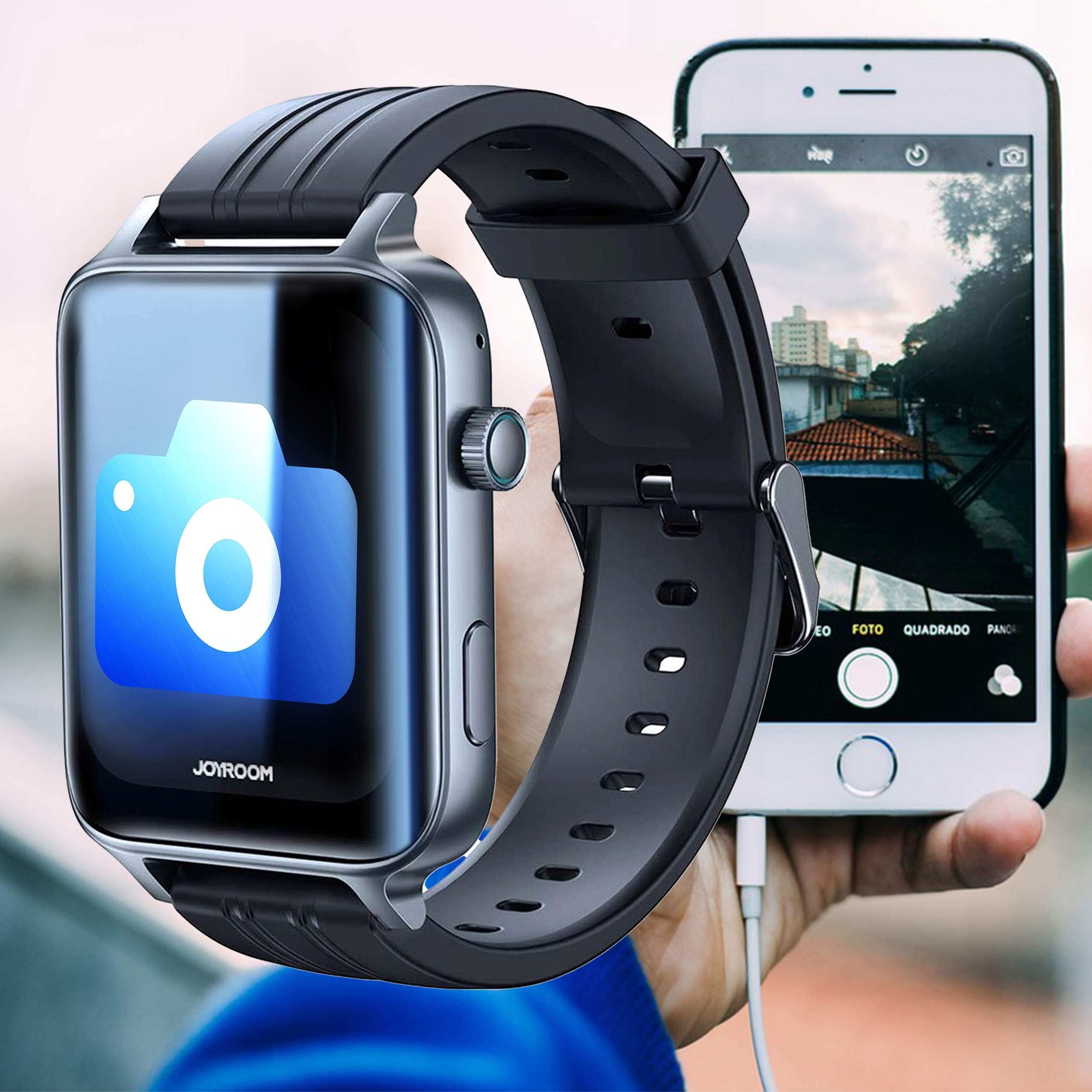 Czarny smartwatch z ikoną aparatu i telefonem. Telefon wyświetla scenę uliczną. Jedna ręka trzyma oba urządzenia.
