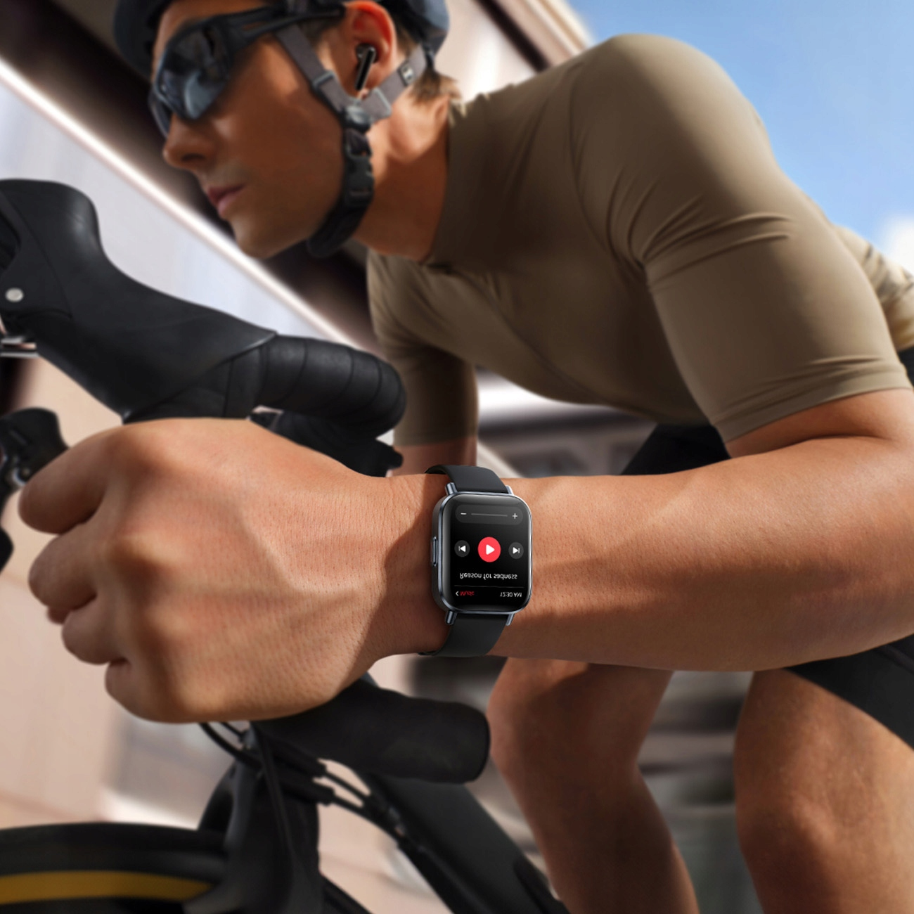 Kolarz w kasku i okularach przeciwsłonecznych jedzie na rowerze. Smartwatch pokazuje aplikację muzyczną, odtwarzającą piosenkę. Tło jest rozmyte.