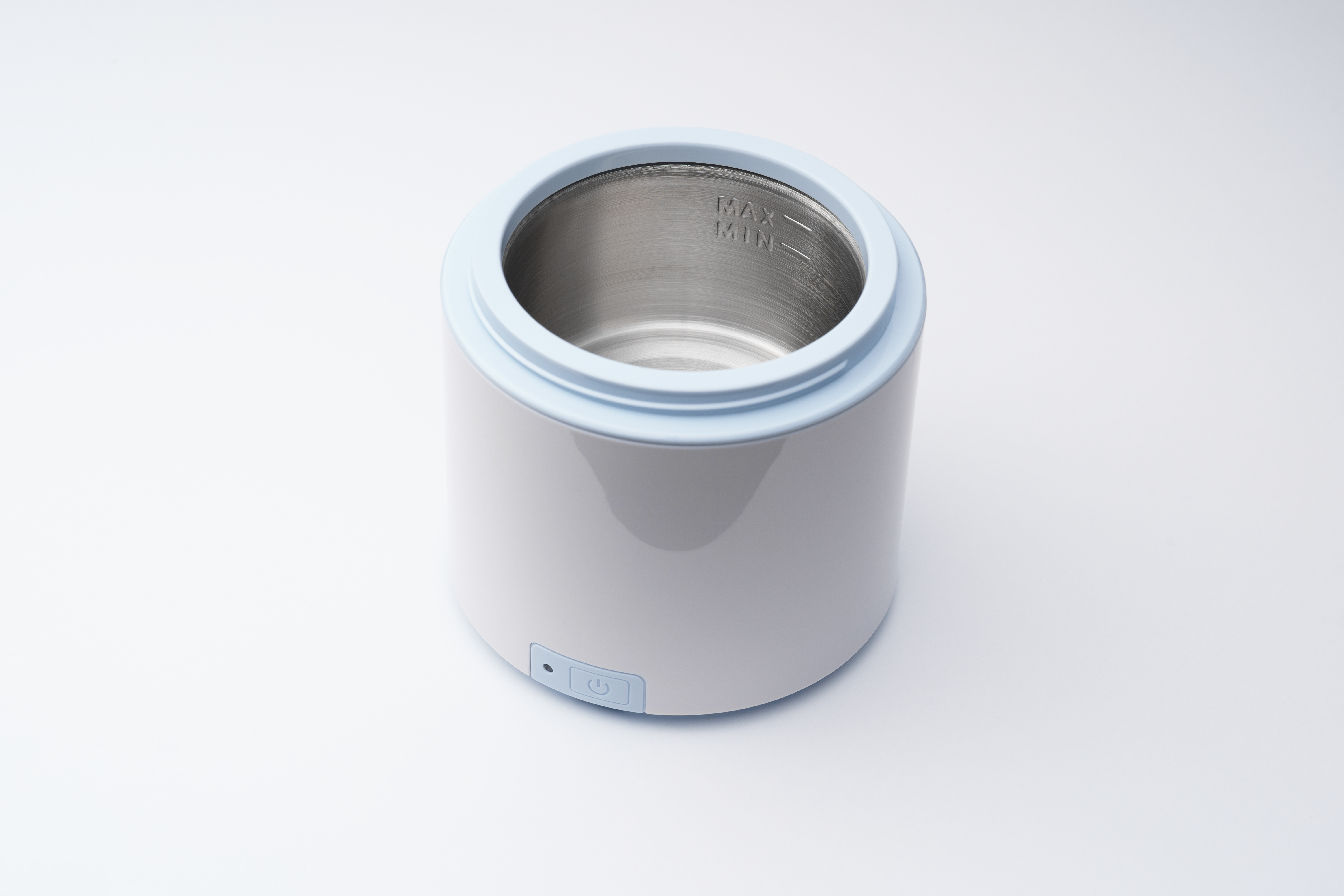 Biało-niebieski podgrzewacz do butelek dla dzieci na białej powierzchni. Ma przycisk zasilania.