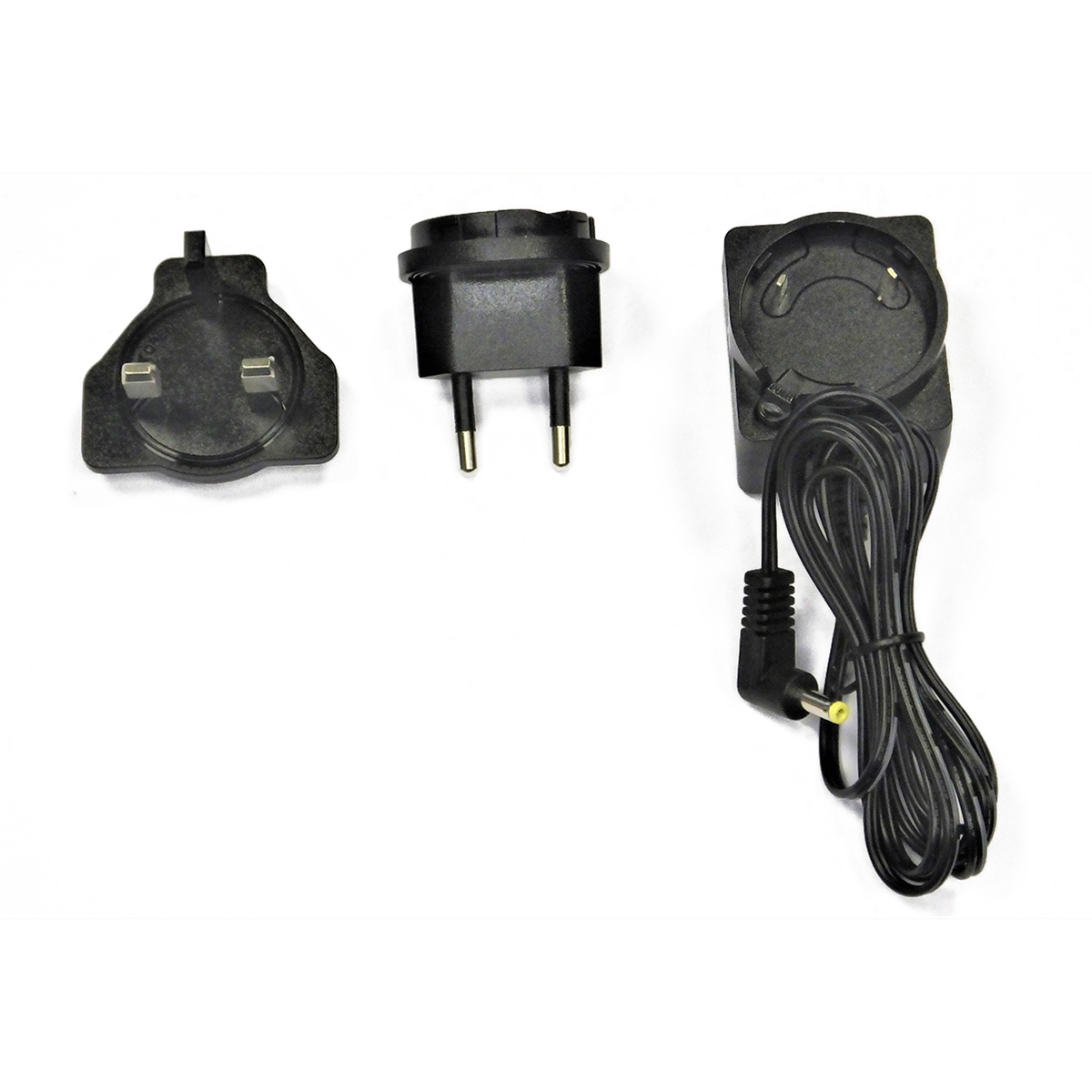 Trzy czarne zasilacze na białej powierzchni. Jeden to wtyczka brytyjska, drugi europejska, a ostatni ma czarny kabel.