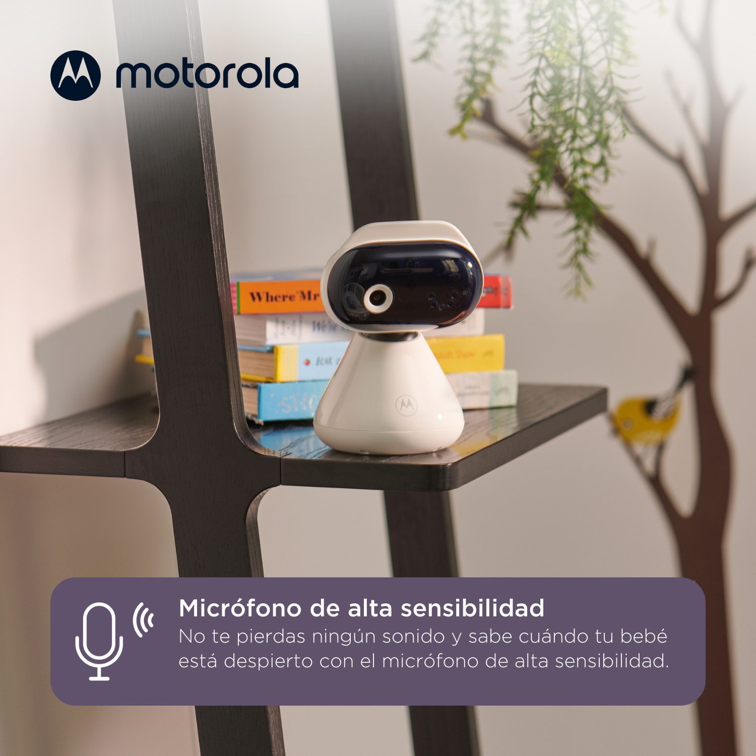 Ein weißer Babyphone mit dunklem Kopf steht auf einem Regal mit Büchern. Motorola-Logo sichtbar. Ein Baum schmückt die Wand.
