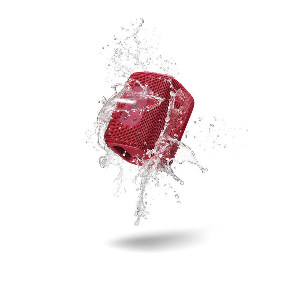 Un altoparlante rosso è circondato da spruzzi d'acqua, sospeso su sfondo bianco. L'altoparlante è il punto focale.