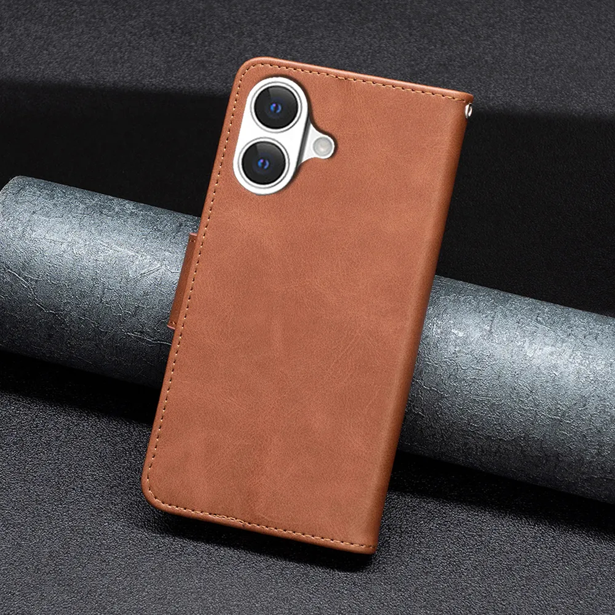 Een bruine leren telefoonhoes met camera-uitsparingen ligt op een gestructureerd oppervlak. De achtergrond is donkergrijs en opgerold.