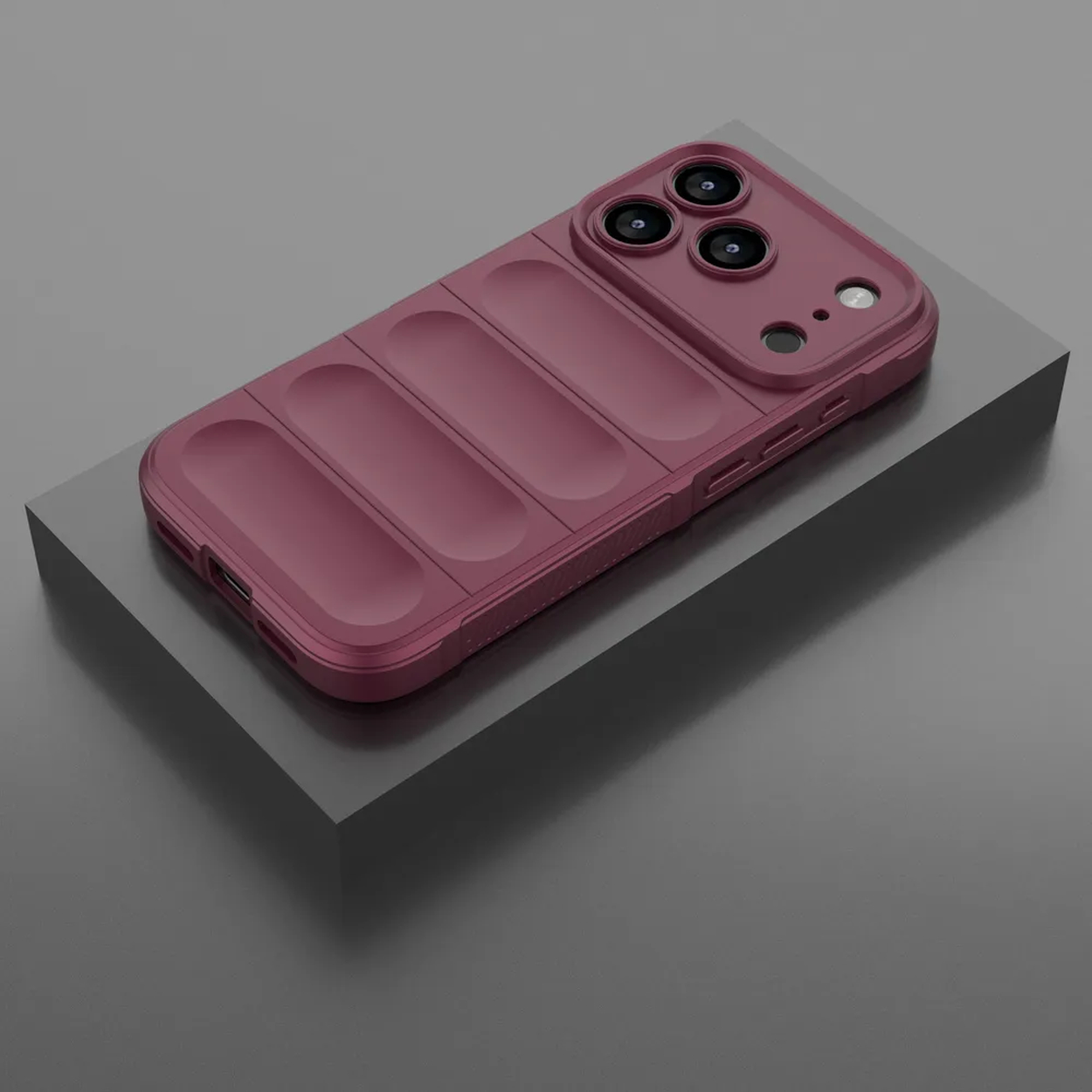 Een bordeauxrode telefoonhoes met uitsparingen voor de camera en een geribbelde achterkant, rustend op een grijs platform tegen een grijze achtergrond.