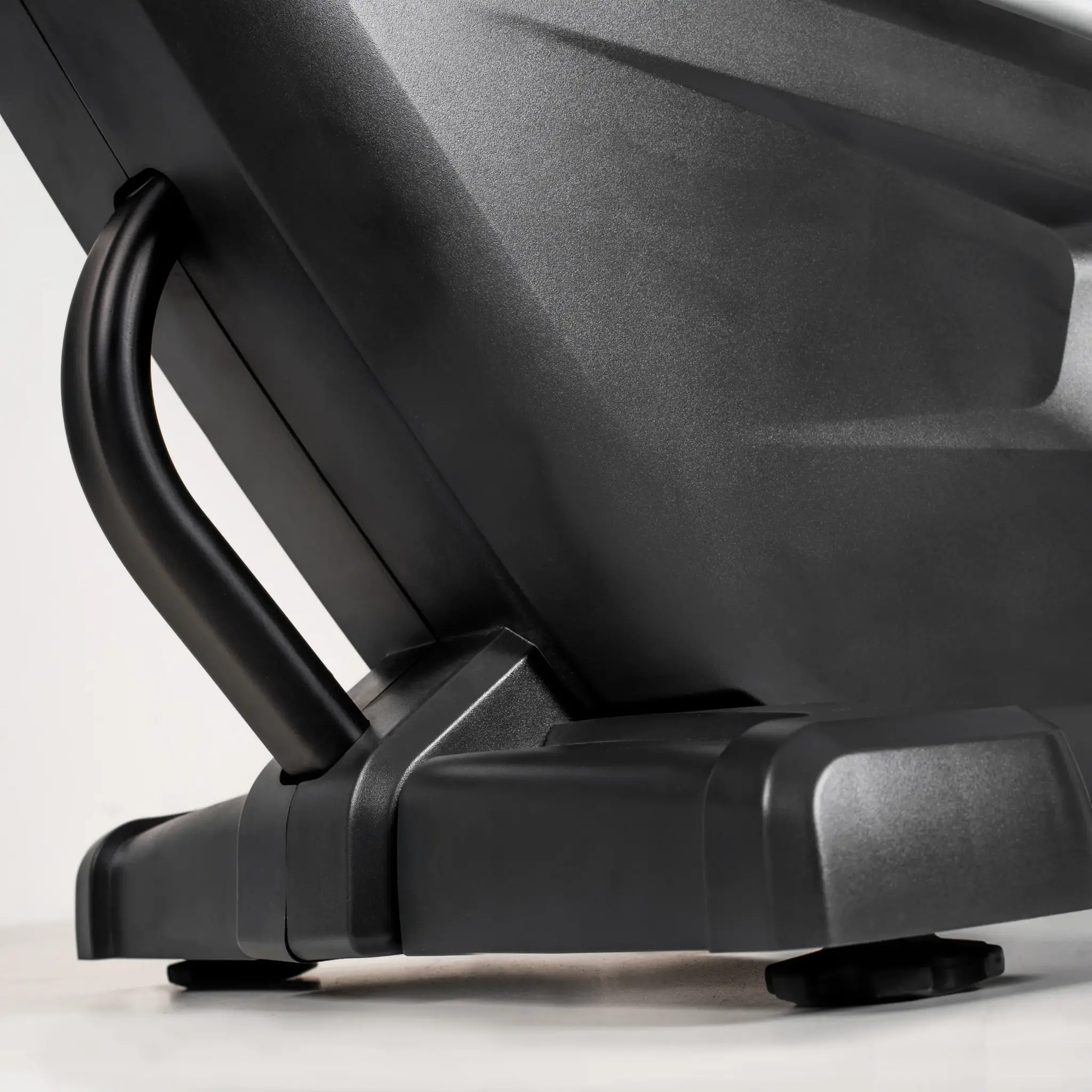 Close-up van een zwarte fitnessmachine. De handgreep en basis zijn zichtbaar tegen een witte achtergrond.