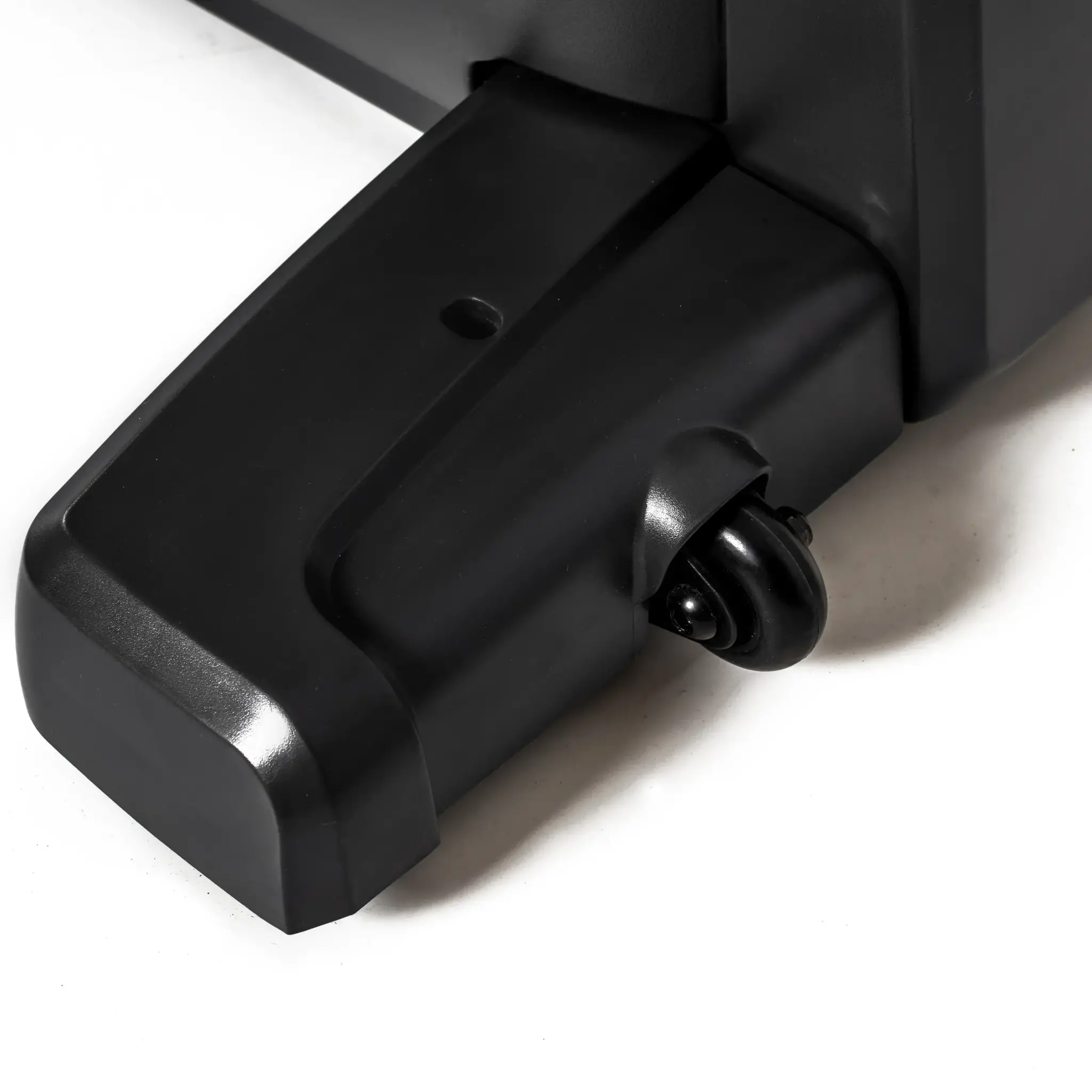 Close-up van een zwart apparatuurbeen. Er is een klein wiel bevestigd. De achtergrond is wit.