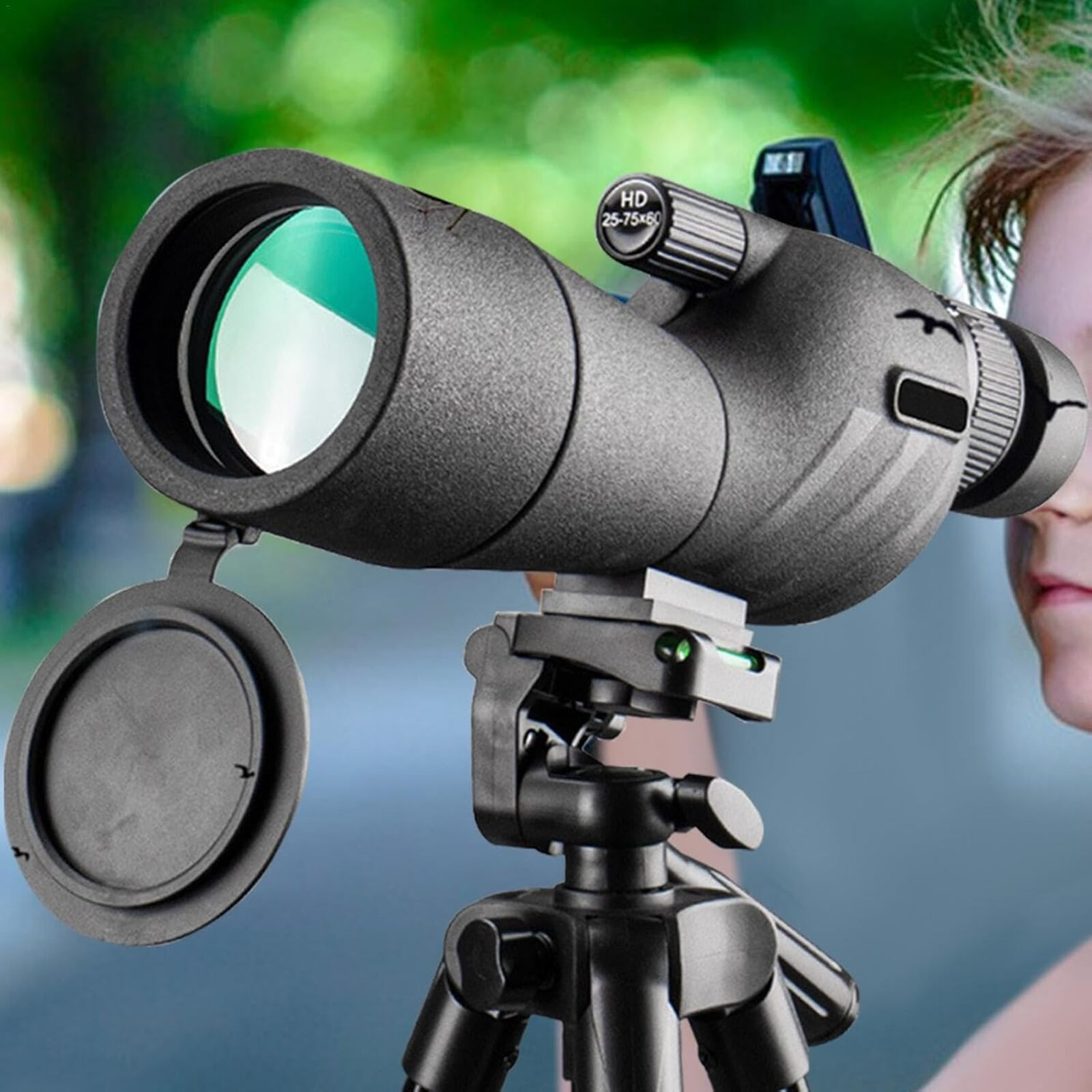 Un telescopio terrestre negro sobre un trípode. El rostro de una persona está en el fondo. El telescopio tiene una lente verde.