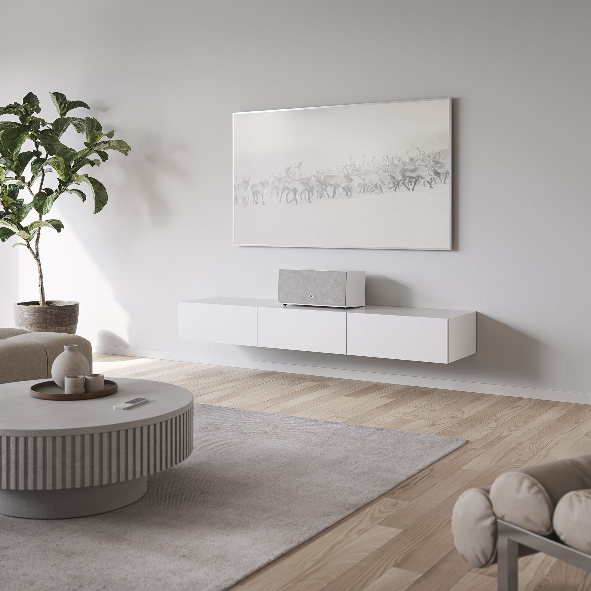 Wohnzimmer mit Rentiergemälde, weißem Schrank, rundem Tisch, Pflanze und grauem Teppich auf Holzboden.