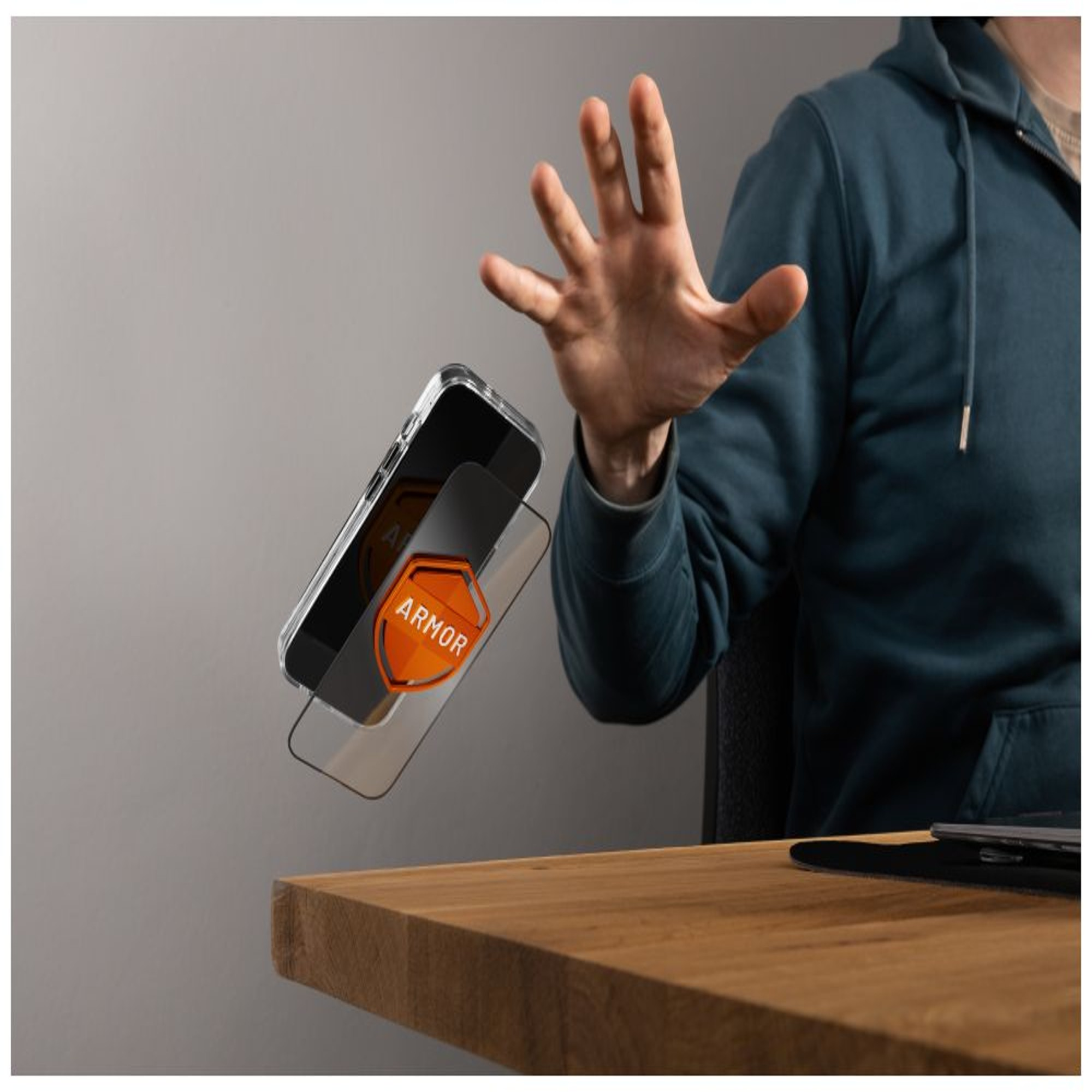La mano di una persona indica una custodia per telefono con protezione per lo schermo. La custodia ha un'etichetta arancione 'ARMOR'.