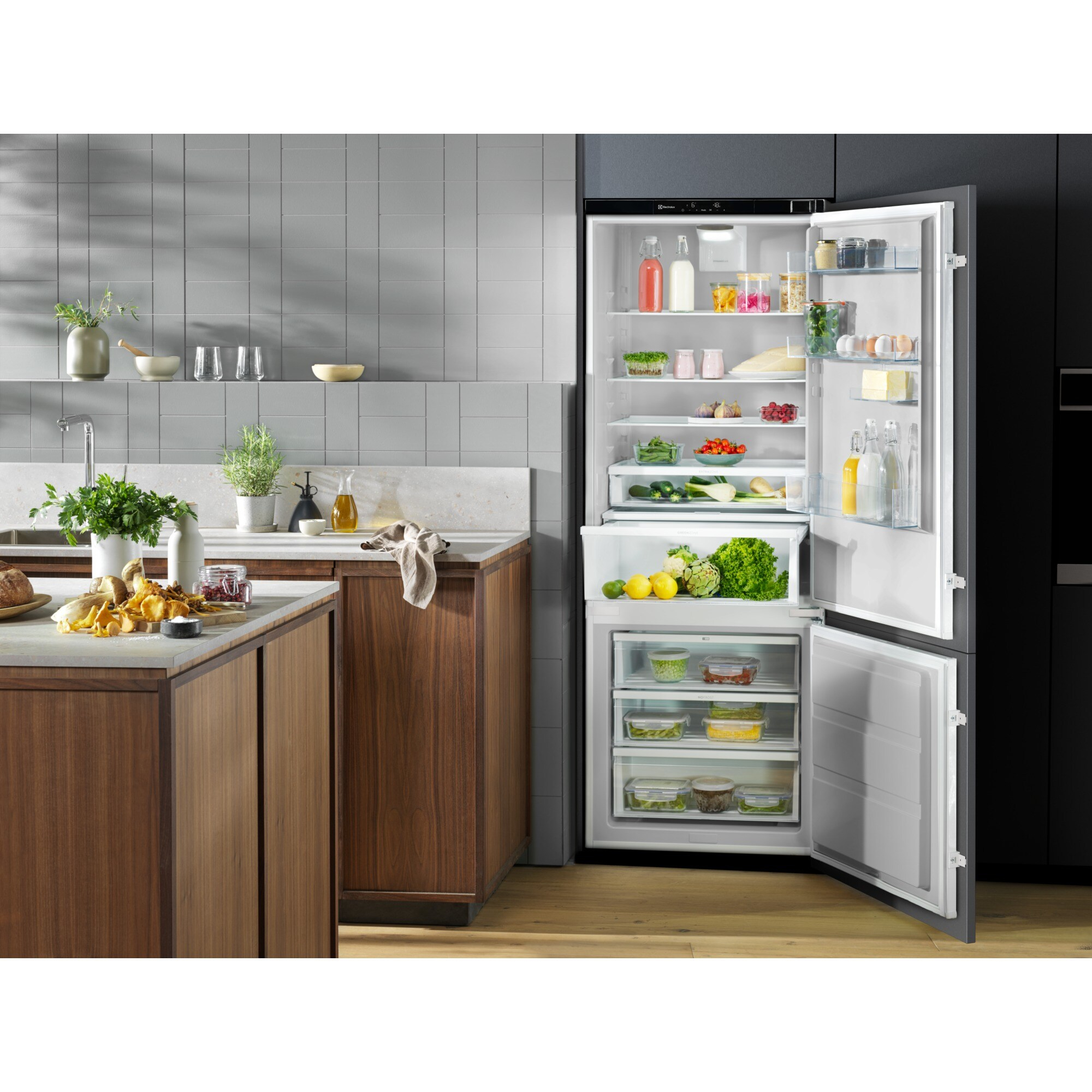 Una cocina con un refrigerador abierto lleno de comida. Frutas, verduras y otros alimentos son visibles. Encimera de cocina con elementos.