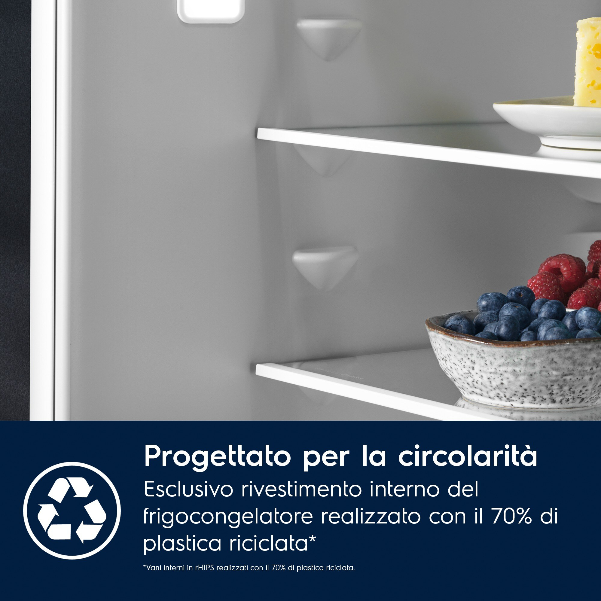Dentro un frigorifero. Ripiani con formaggio, mirtilli e lamponi. Testo: Progettato per la circolarità con plastica riciclata.