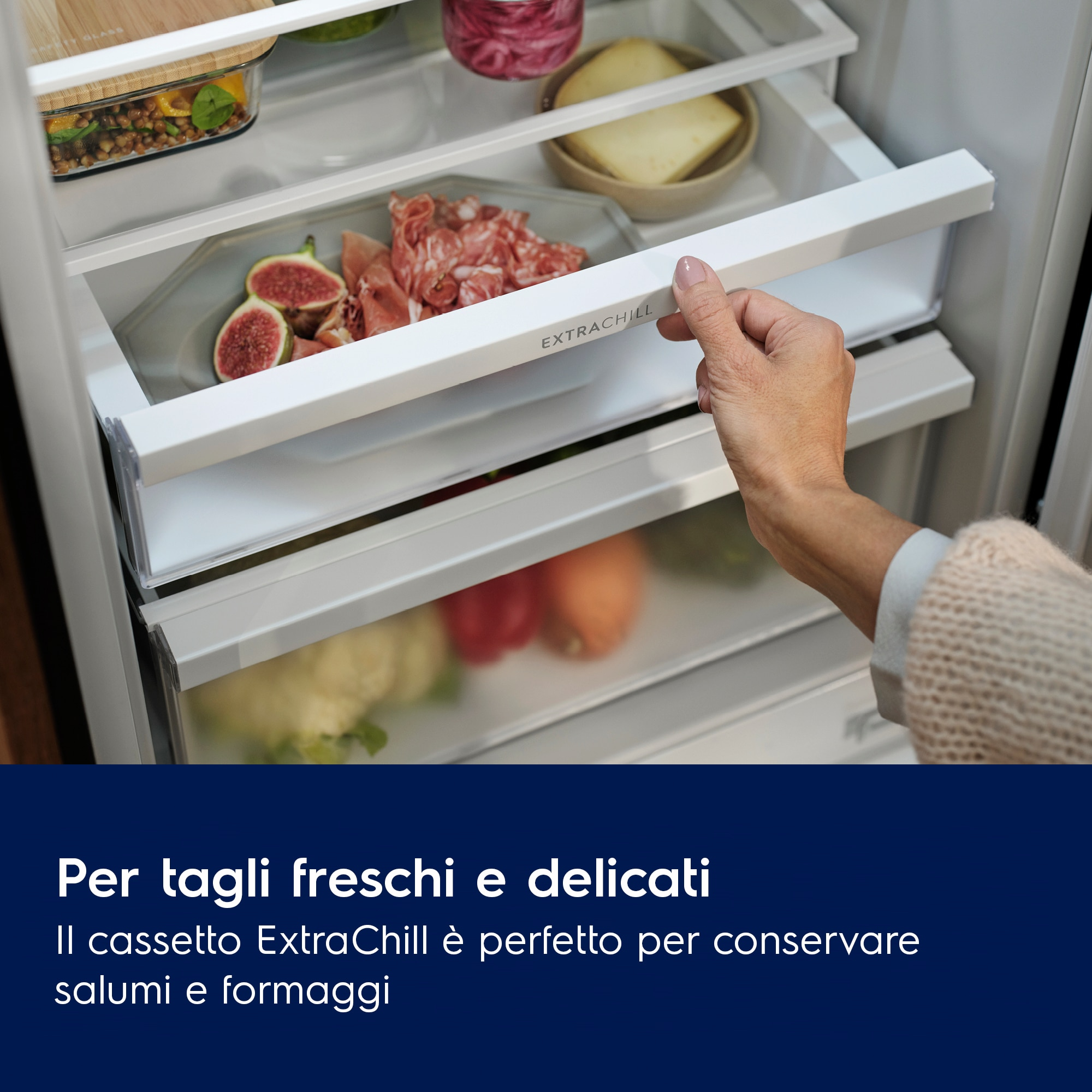 Una mano apre un cassetto ExtraChill in un frigorifero. Il cassetto contiene fichi e salumi.