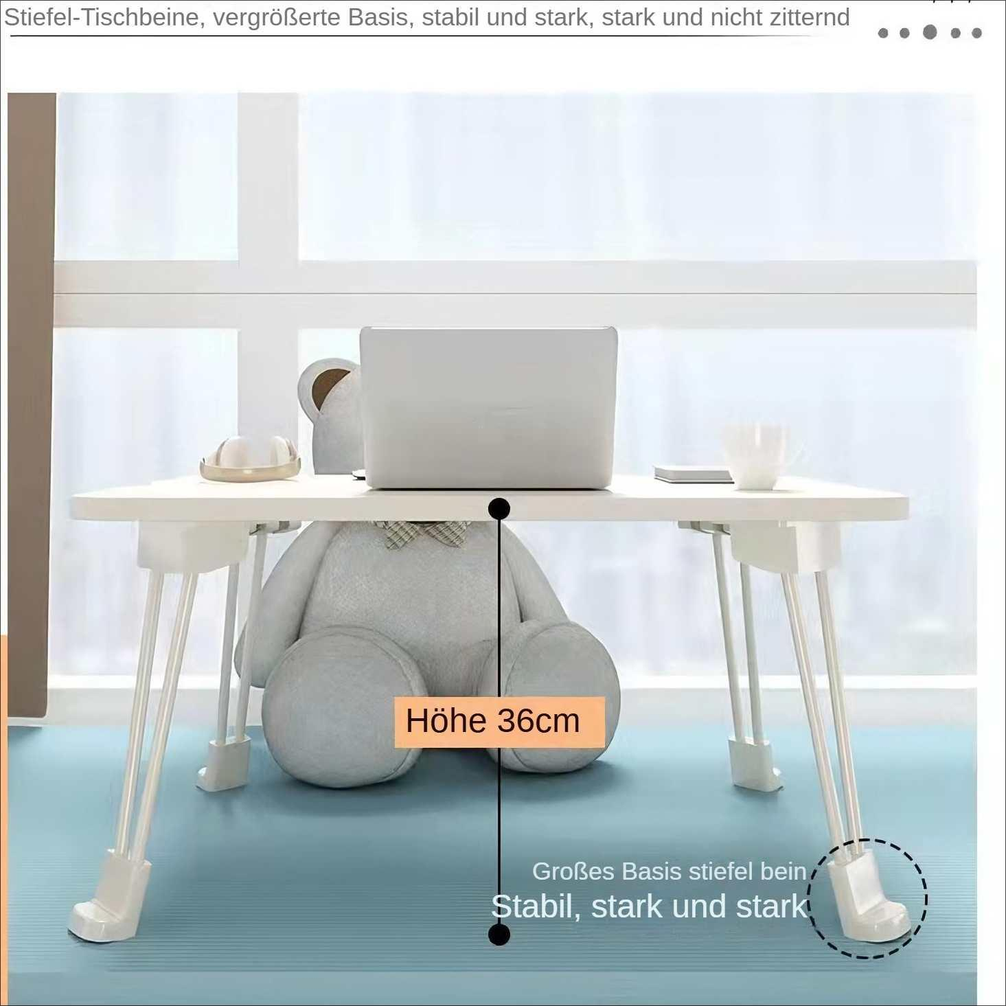 Ein weißer Tisch mit Laptop, Teddybär und Tasse. Die Beine sind weiß. Der Hintergrund ist ein Fenster.