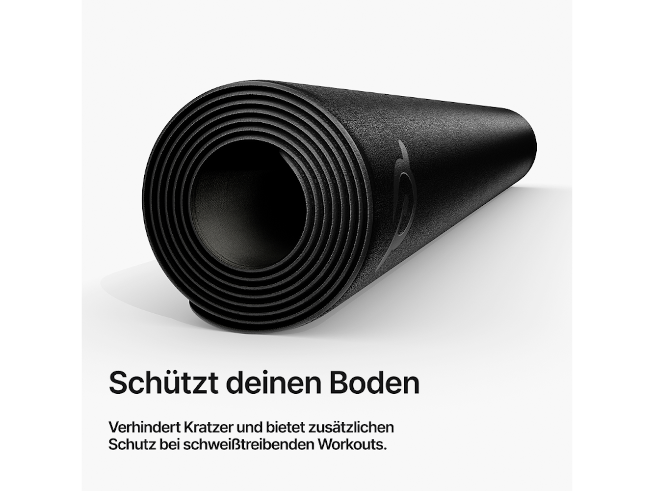 Eine zusammengerollte schwarze Trainingsmatte auf weißem Untergrund. Sie hat ein Logo und schützt den Boden vor Kratzern.