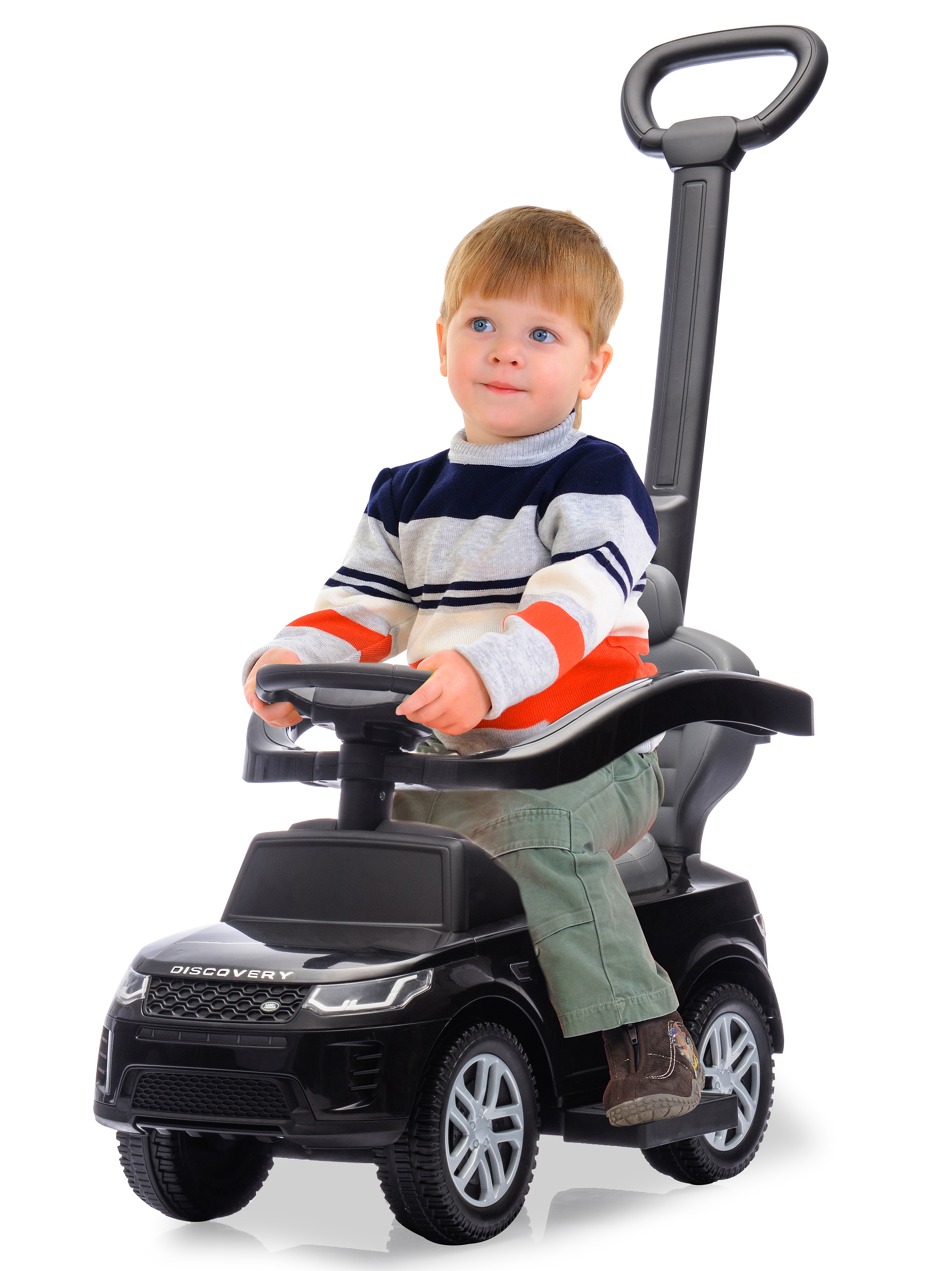 Ein kleiner Junge in einem gestreiften Pullover sitzt in einem schwarzen Spielzeugauto und schaut nach oben.