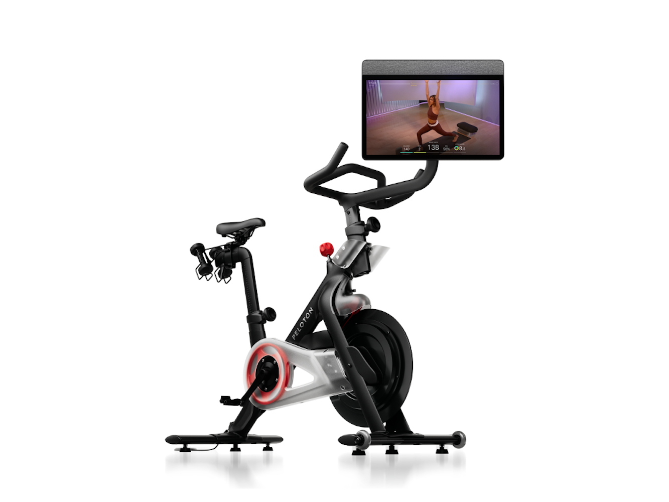 Peloton-Heimtrainer mit Bildschirm. Der Bildschirm zeigt eine Frau in einer Yoga-Pose. Das Fahrrad ist schwarz und silber.