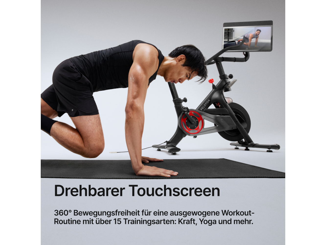 Mann trainiert auf einem Peloton-Fahrrad. Er liegt auf einer Matte, mit einem Bildschirm, der ein Training zeigt.