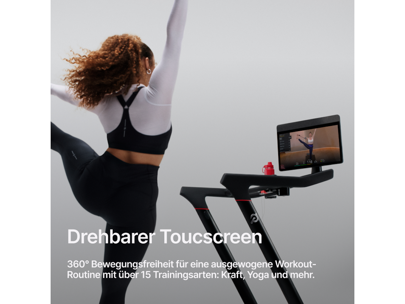 Eine Frau in Sportkleidung praktiziert Yoga vor einem Laufband mit einem Bildschirm. Eine Wasserflasche steht auf dem Laufband.