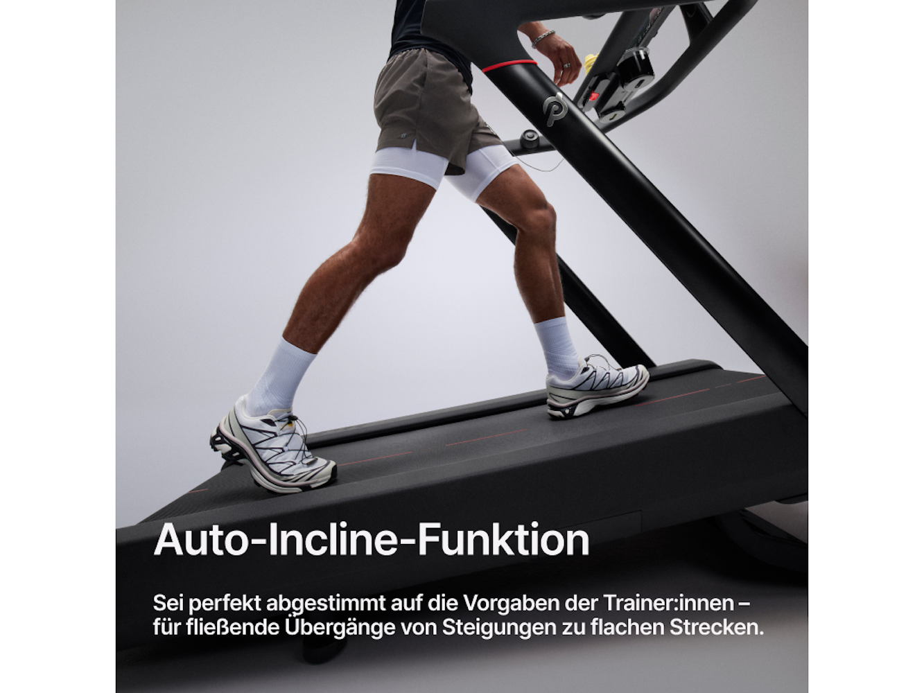 Ein Mann läuft auf einem Laufband. Er trägt Shorts, weiße Socken und Laufschuhe. Das Laufband ist schwarz, und darunter steht Text.