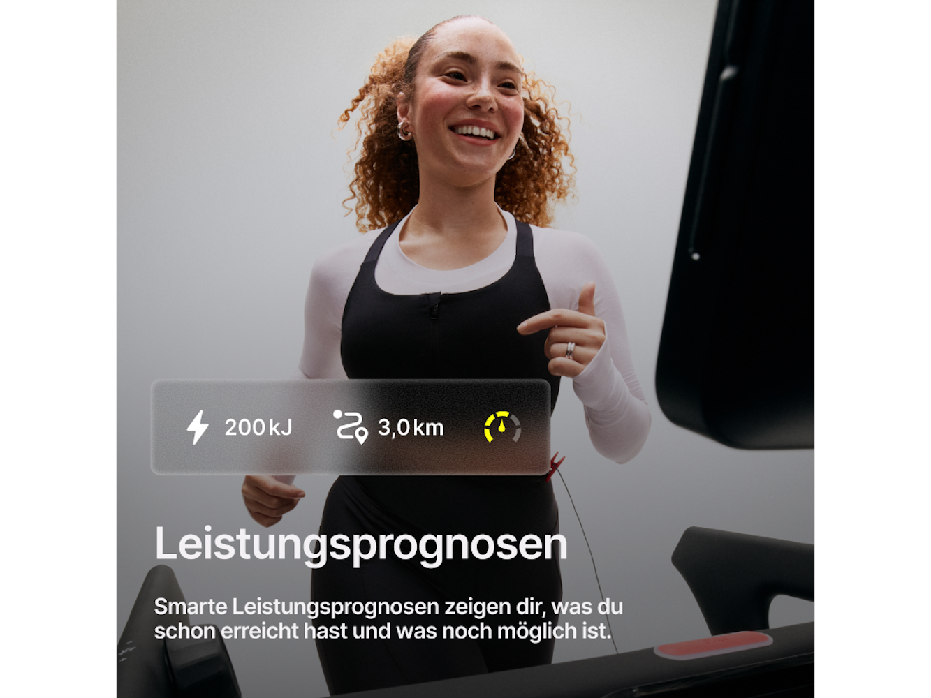Eine Frau läuft auf einem Laufband und lächelt. Sie trägt ein schwarzes Oberteil und weiße Ärmel. Statistiken: 200kJ, 3,0 km und ein Energiesymbol.