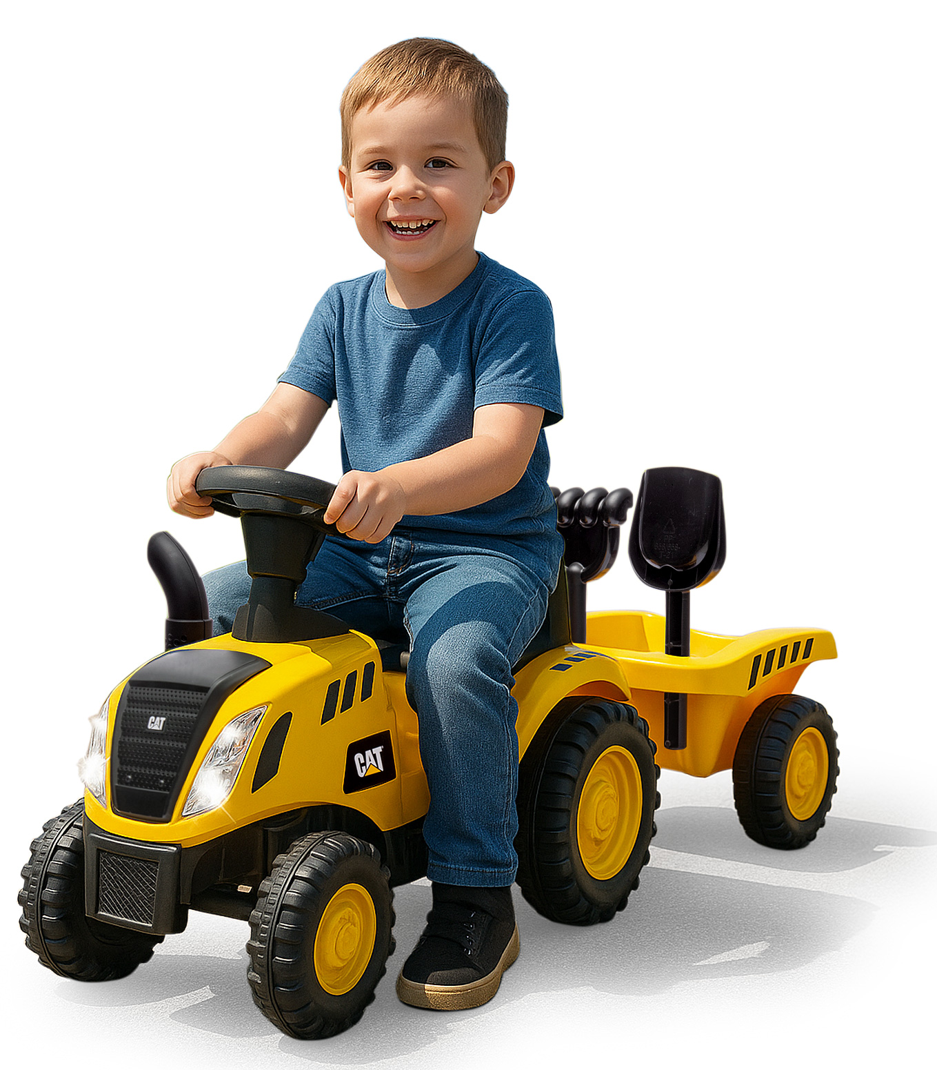 Ein lächelnder Junge in blauer Kleidung sitzt auf einem gelben CAT-Spielzeugtraktor. Der Traktor hat einen Anhänger. Weißer Hintergrund.