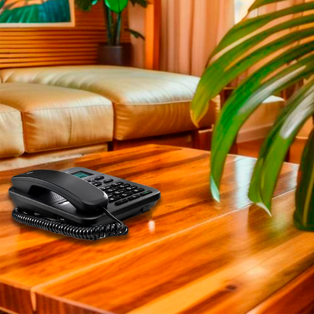 Un teléfono negro está sobre una mesa de madera. Un sofá está en el fondo. Hojas verdes están en el lado derecho de la imagen.