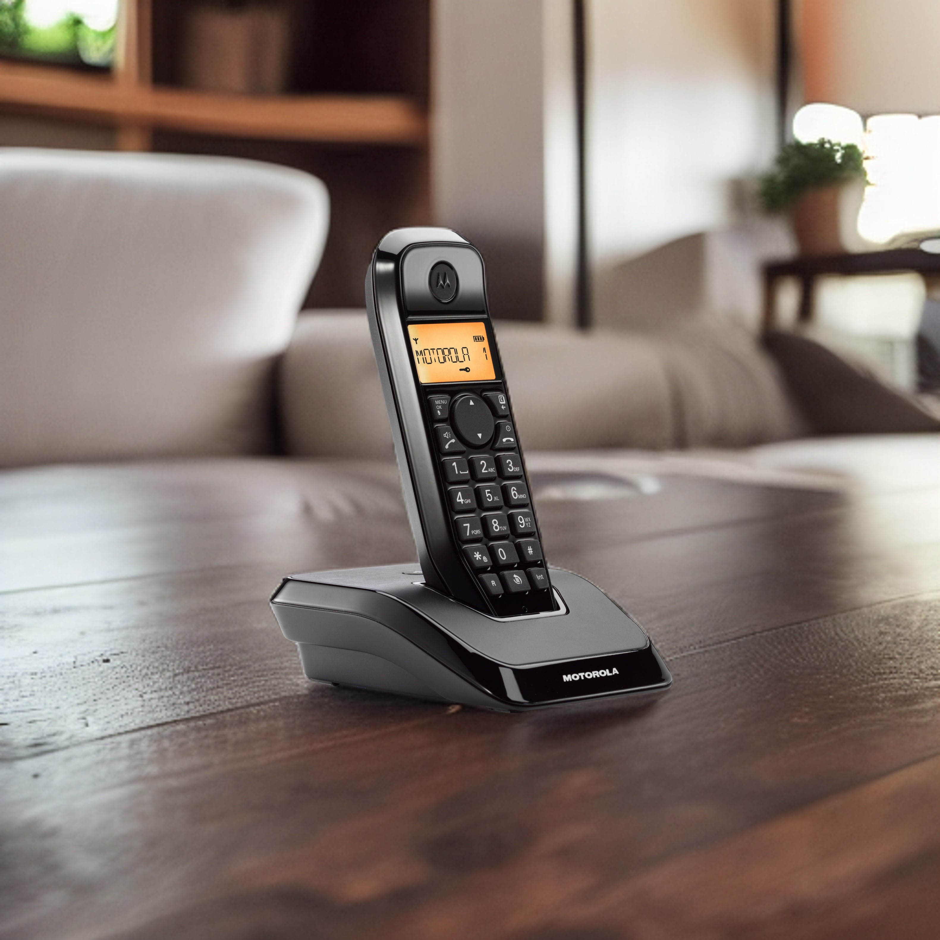 Ein schwarzes schnurloses Motorola-Telefon auf einem Holztisch. Der Bildschirm zeigt 'MOTOROLA 1'. Im Hintergrund ist ein Sofa.
